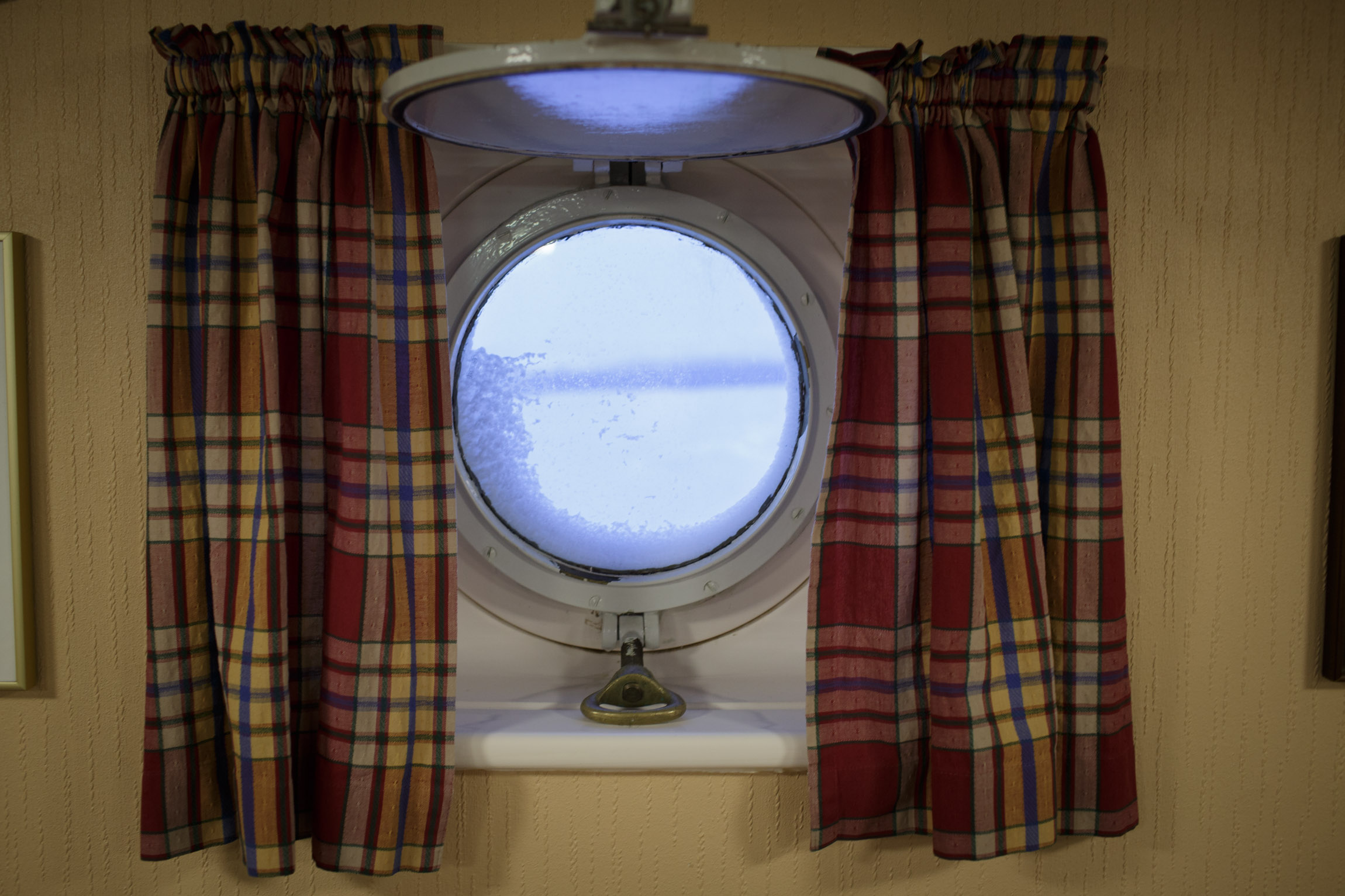 Curtains hang over a ship's porthole