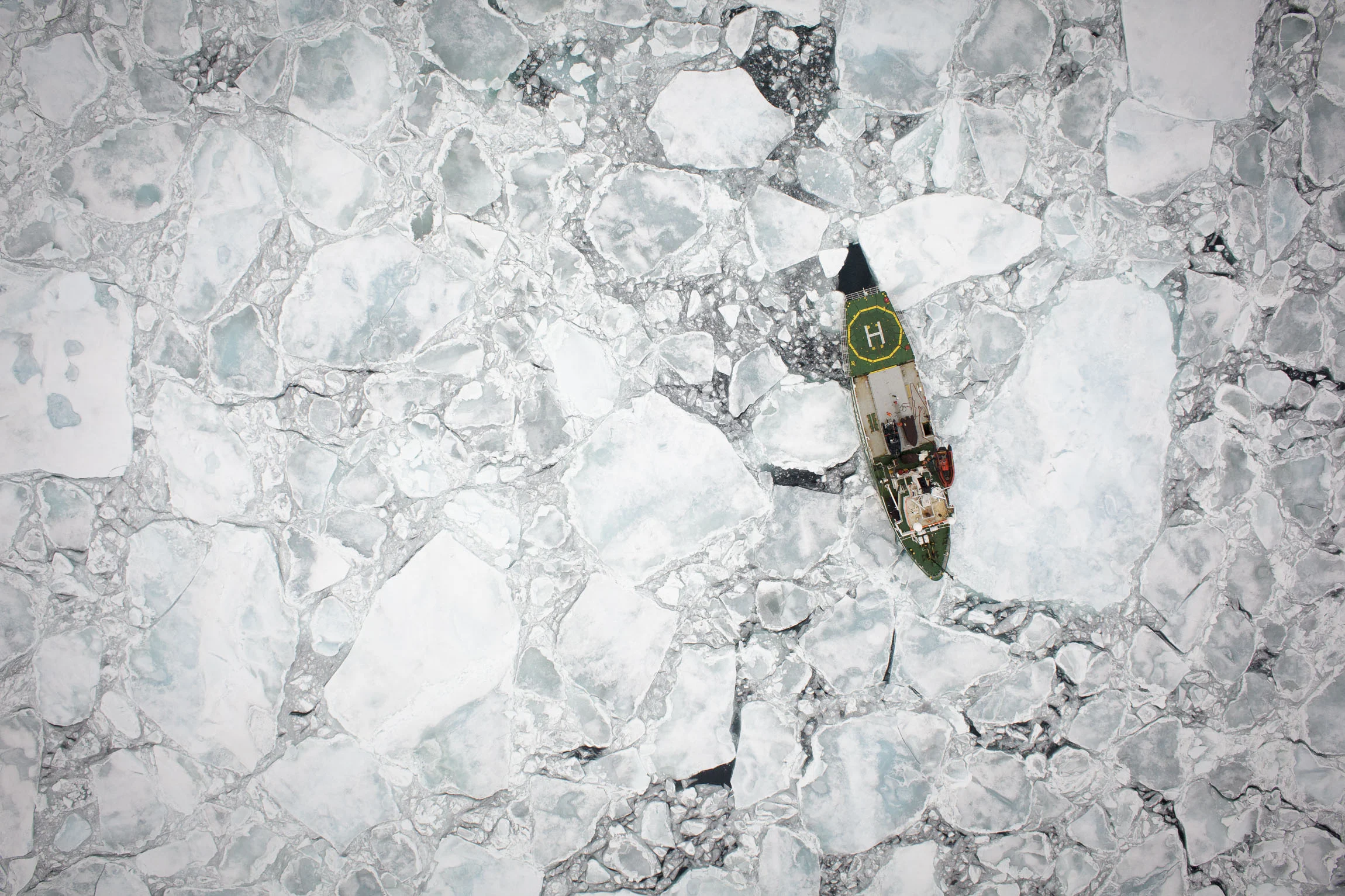 A tiny ship photographed from the air in Arctic sea ice