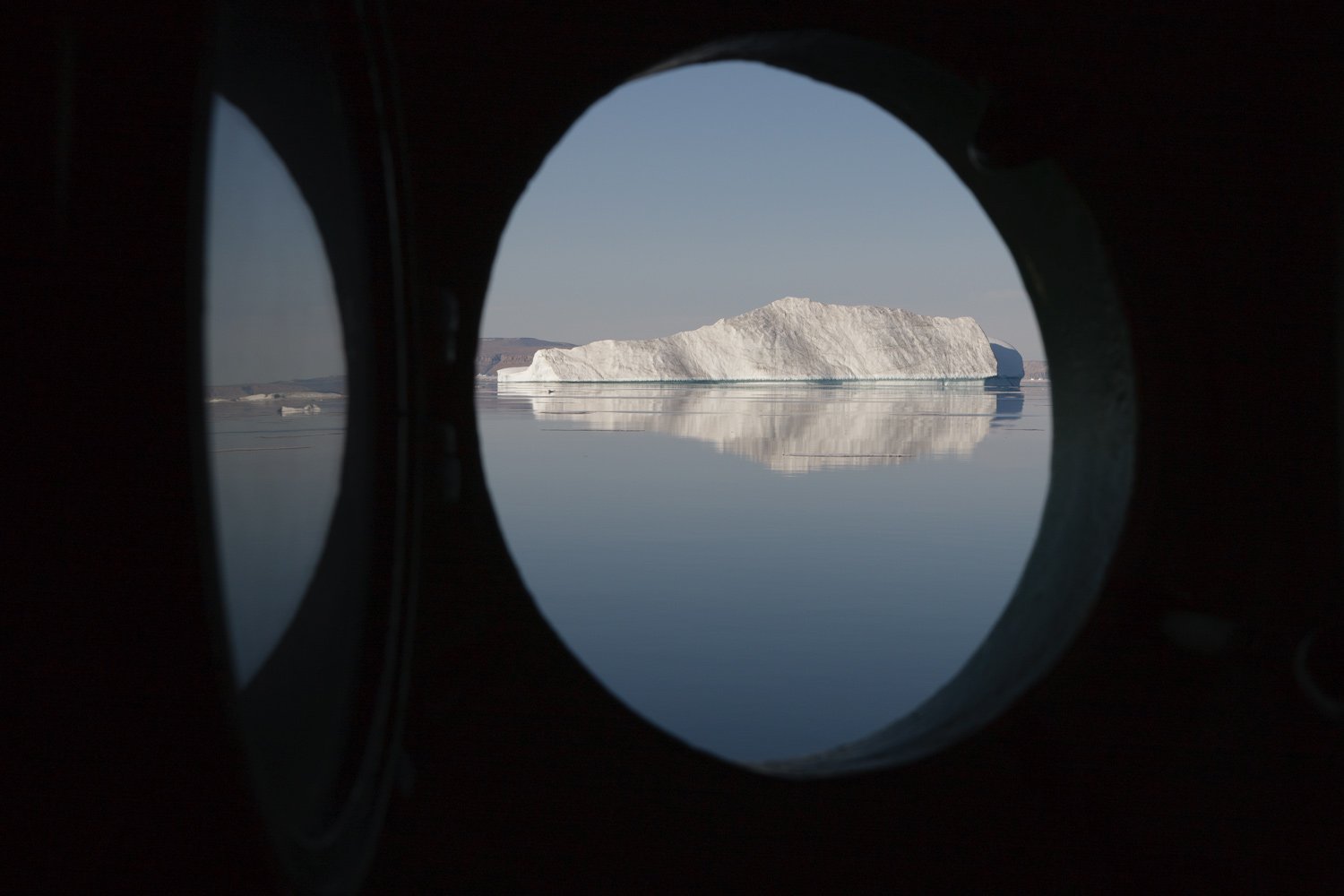 Iceberg framed by ship's porthole