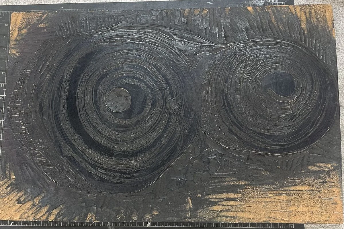 A wood block with the image of a birch curl carved into it
