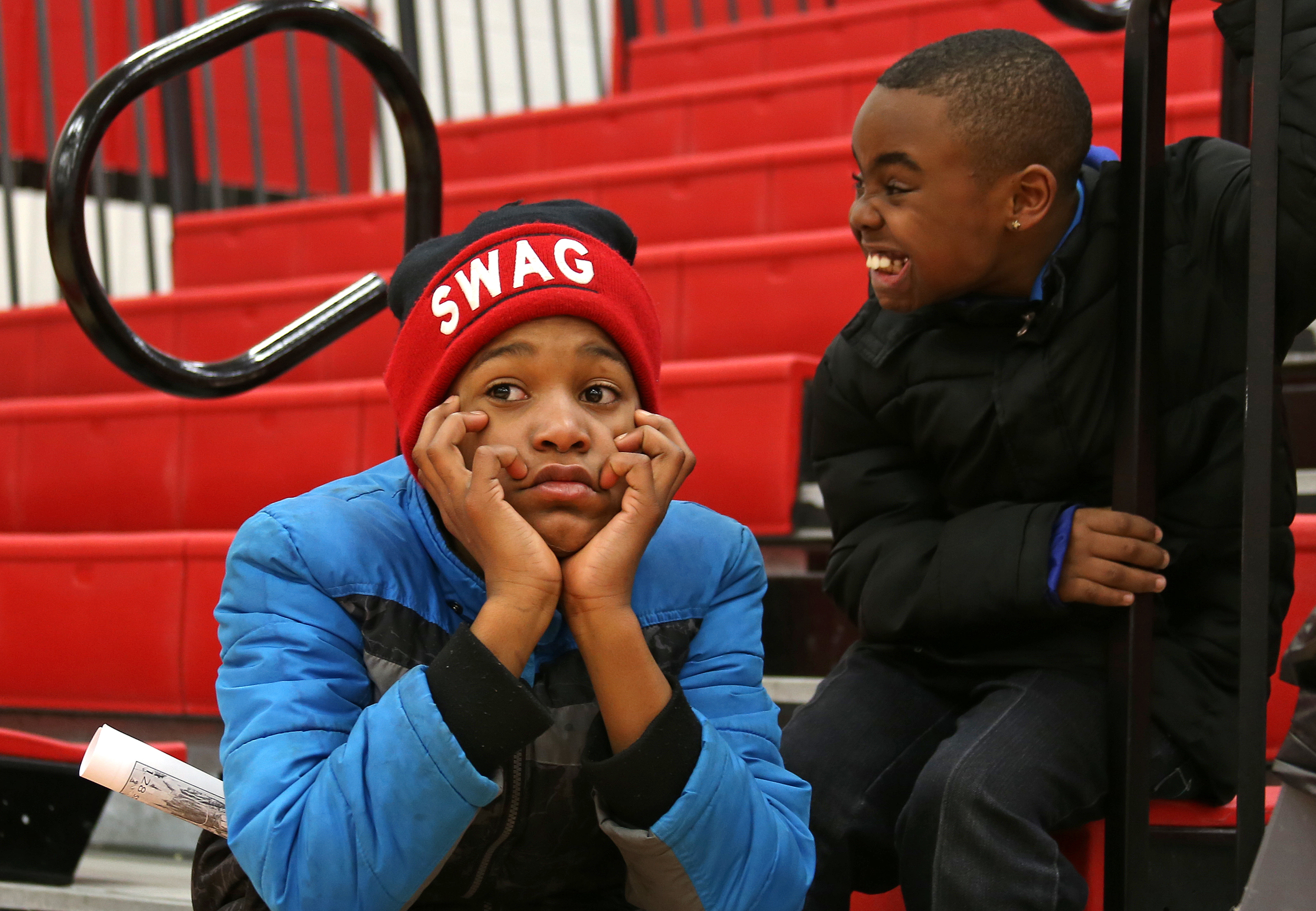 Muskegon Heights Academy fans, Dajuan Garrett, 11, center, and Jamarion Diggs, 9, right, watch the North Muskegon team warm-up on the court before their Class C boys basketball district championship game against Muskegon Heigths at Kent City High School.