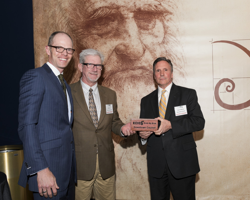 Sean O’Byrne (right) and Bill Dietrich (middle) of the Downtown Council take home a Brick by Brick award for their conversion of a halfway house in the West Bottoms to a minimum security prison.