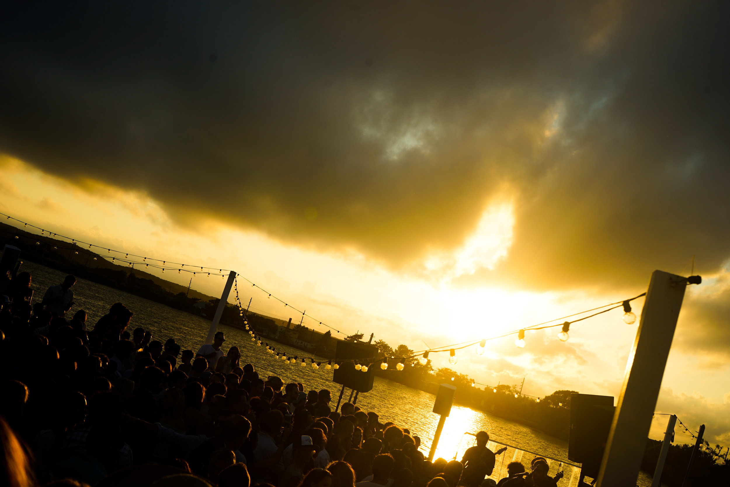 Overlooking a crowded party on the waterfront at sunset. 