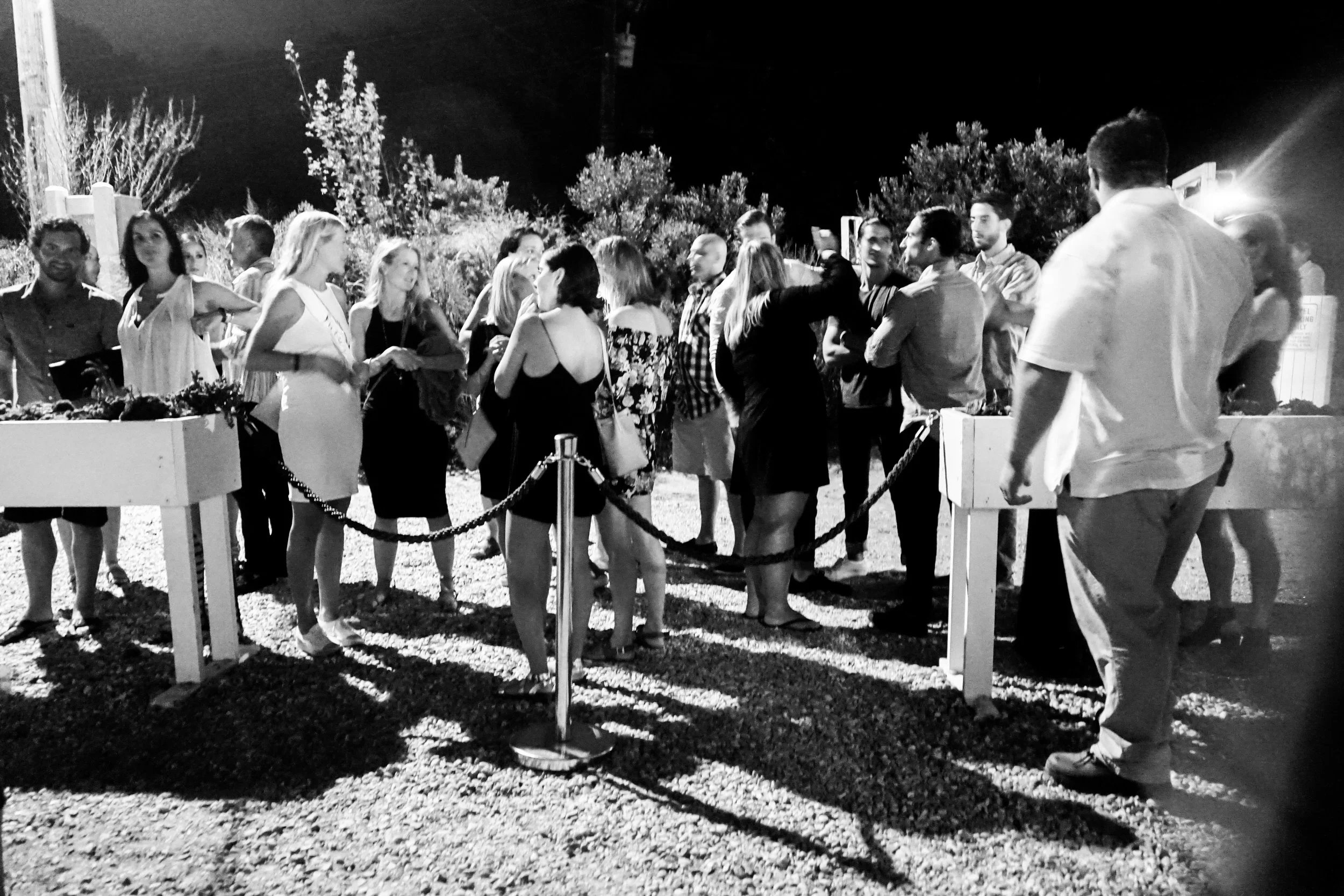 A crowded party on the beach, behind a roped off section.