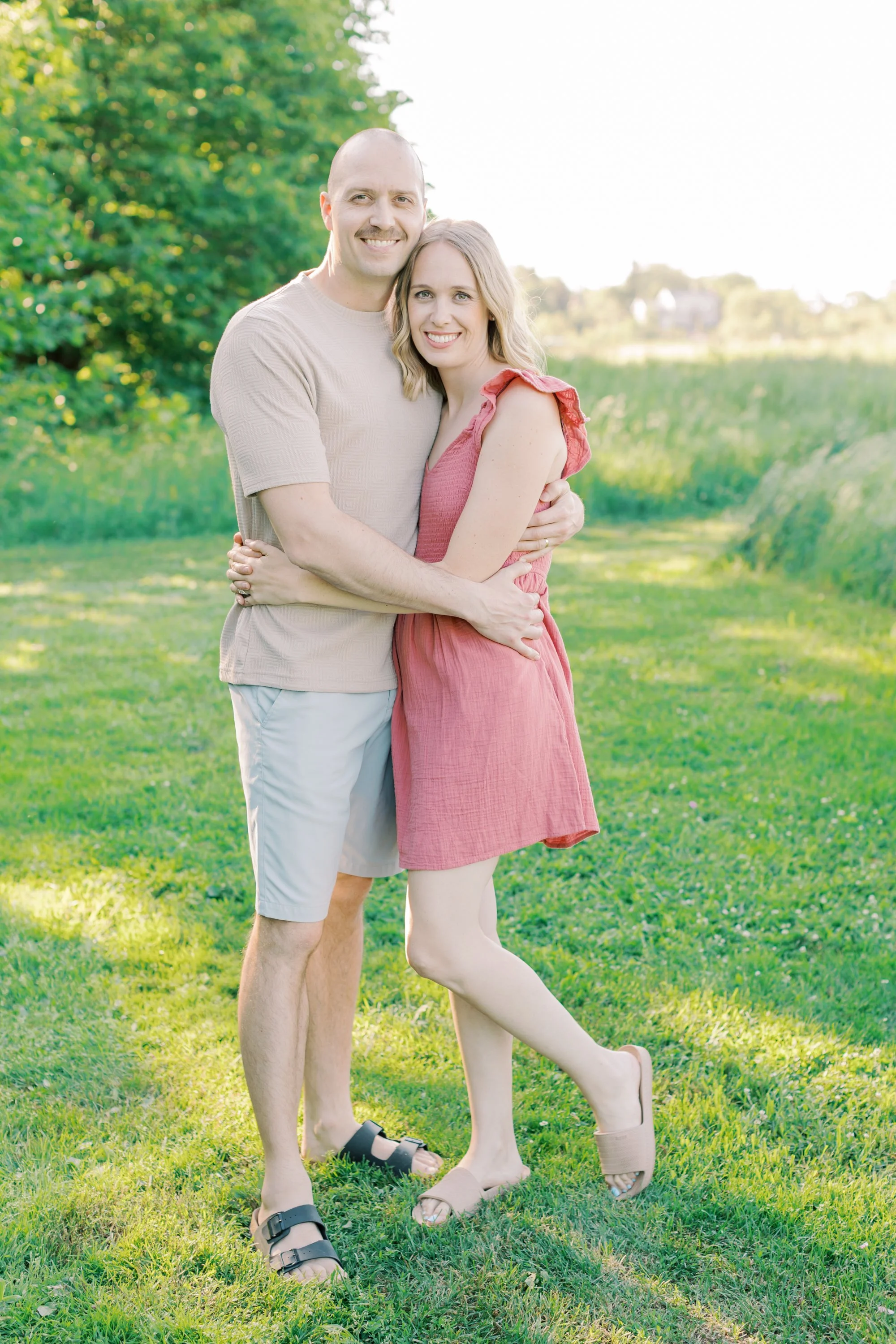 A candid and emotional family portrait captured by a Burlington family photographer in an open, natural field.