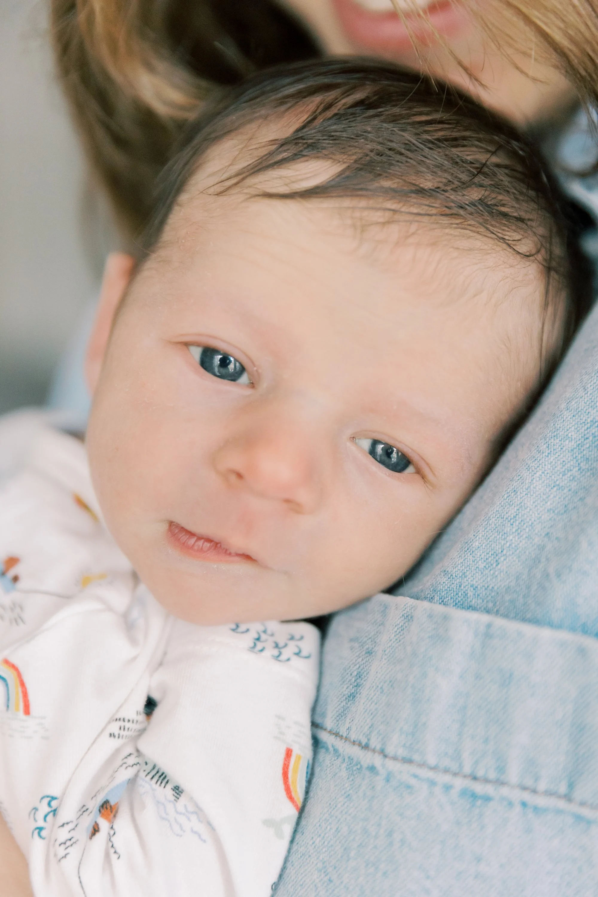 Mother cuddling newborn during a natural newborn photography session in an Oakville home.