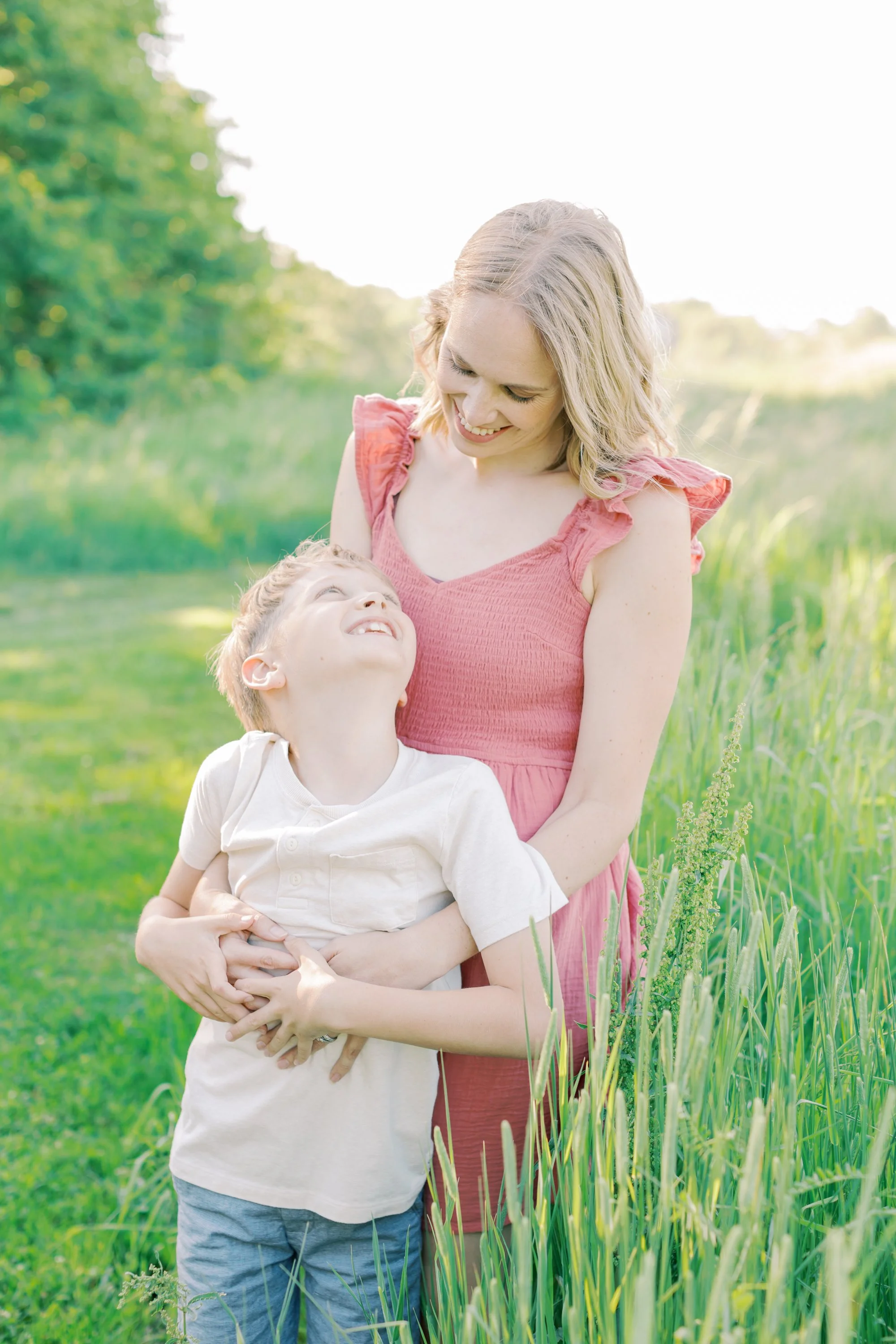 A candid and emotional family portrait captured by a Burlington family photographer in an open, natural field.