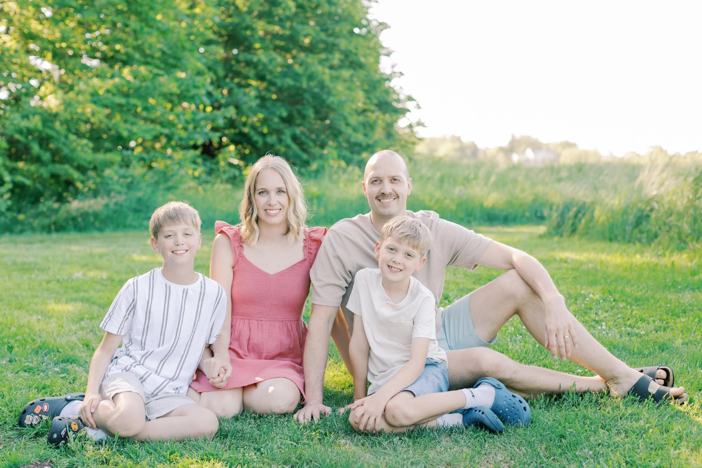 A candid and emotional family portrait captured by a Burlington family photographer in an open, natural field.