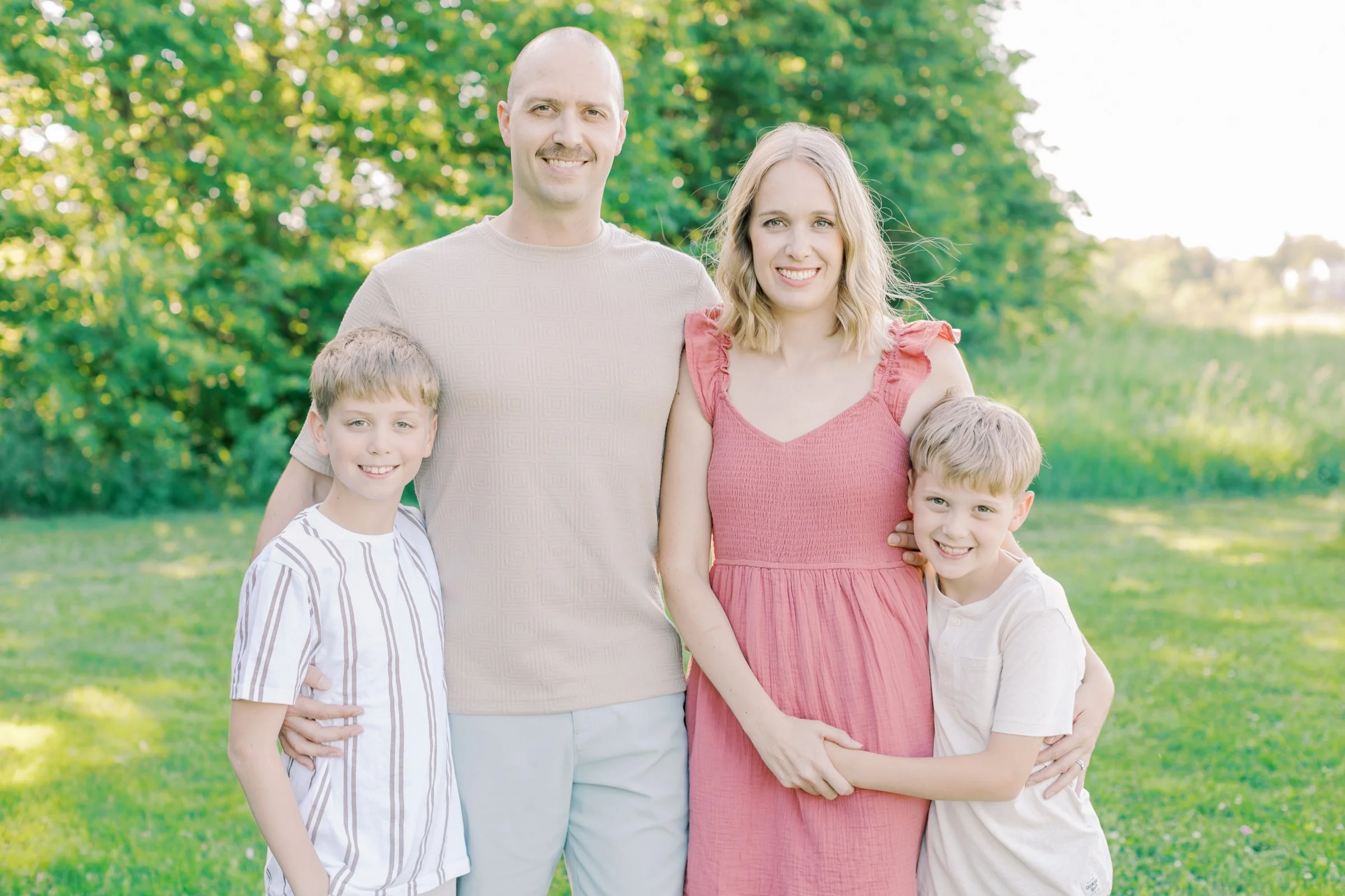 A candid and emotional family portrait captured by a Burlington family photographer in an open, natural field.
