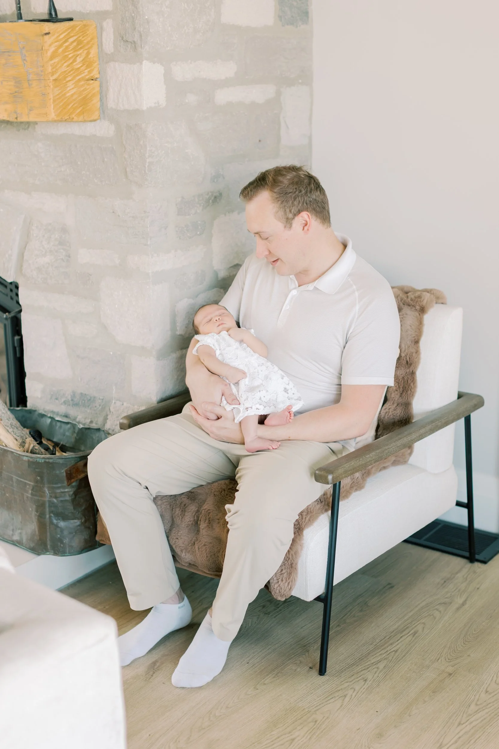 A tiny newborn sleeping soundly in a parent's arms, illustrating a successful, stress-free moment of an in-home shoot.