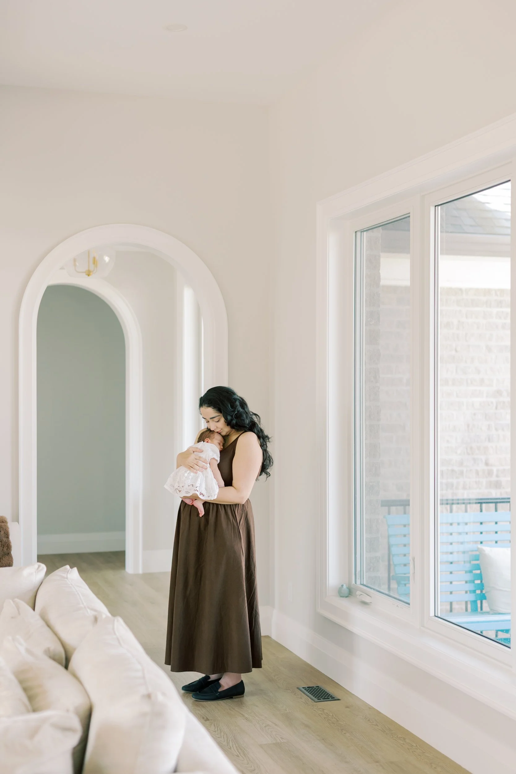 A tiny newborn sleeping soundly in a parent's arms, illustrating a successful, stress-free moment of an in-home shoot.