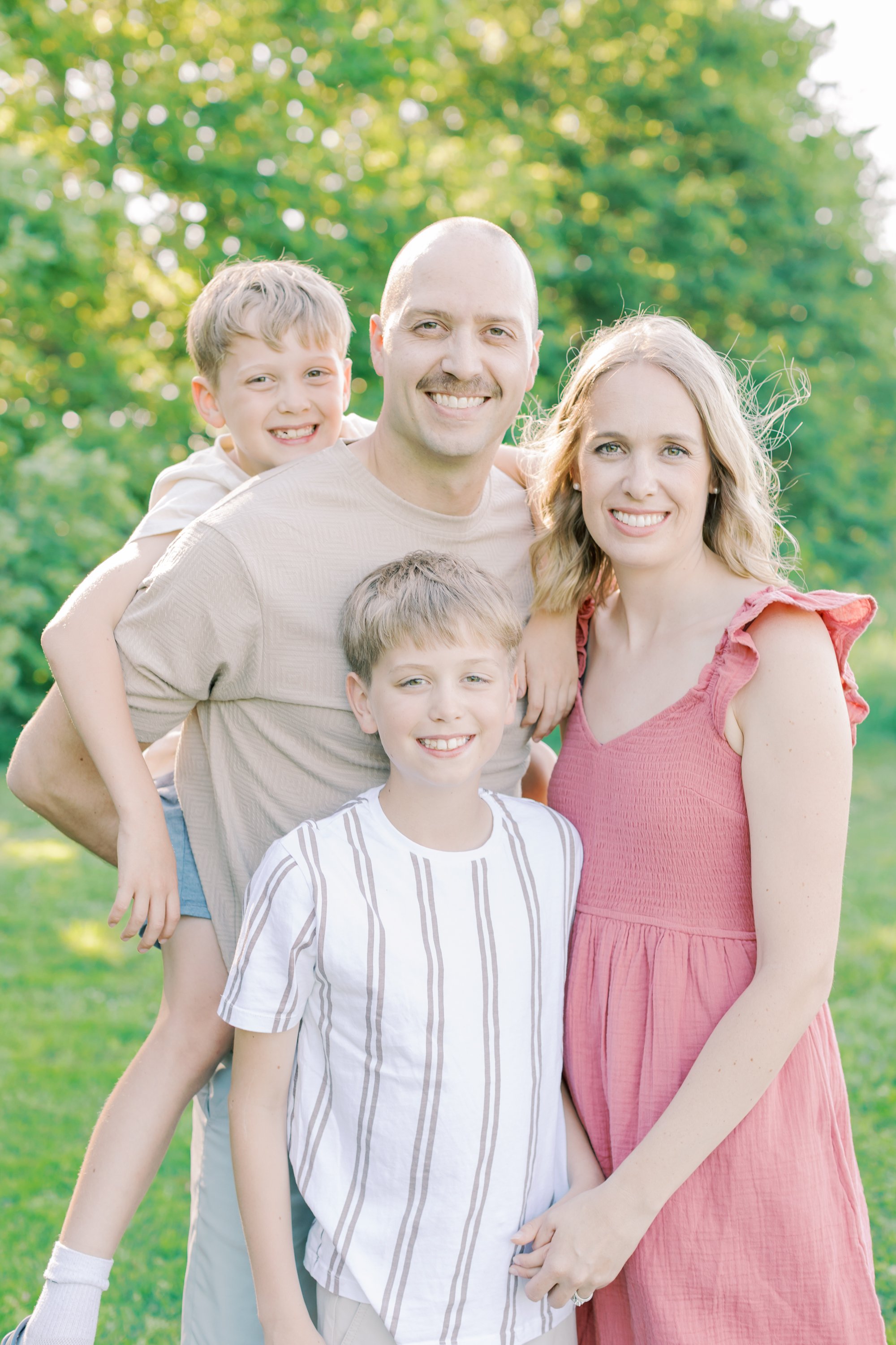 A candid and emotional family portrait captured by a Burlington family photographer in an open, natural field.
