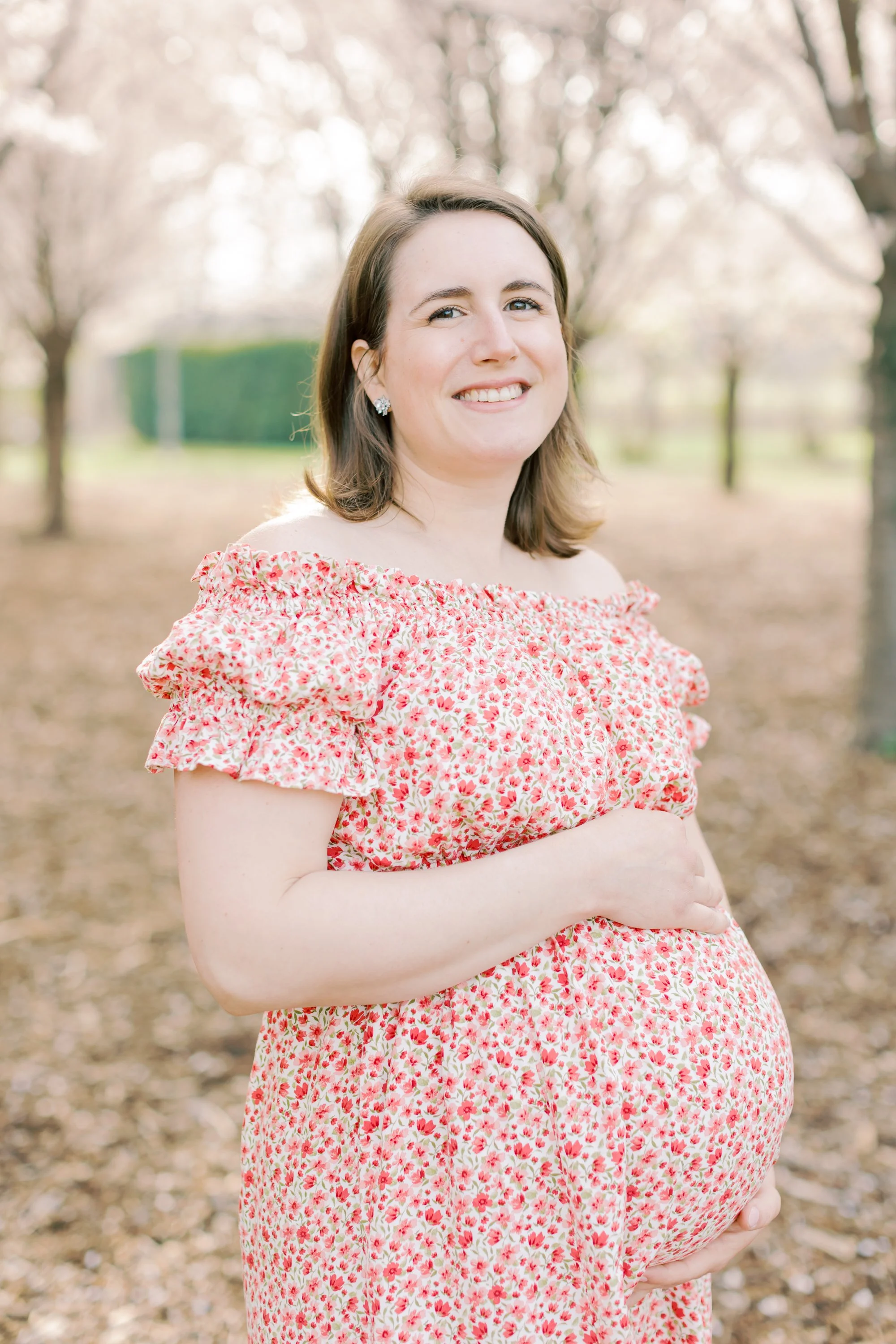 A pregnant mother and her toddler son under cherry blossom trees during a maternity session in Burlington, Ontario.