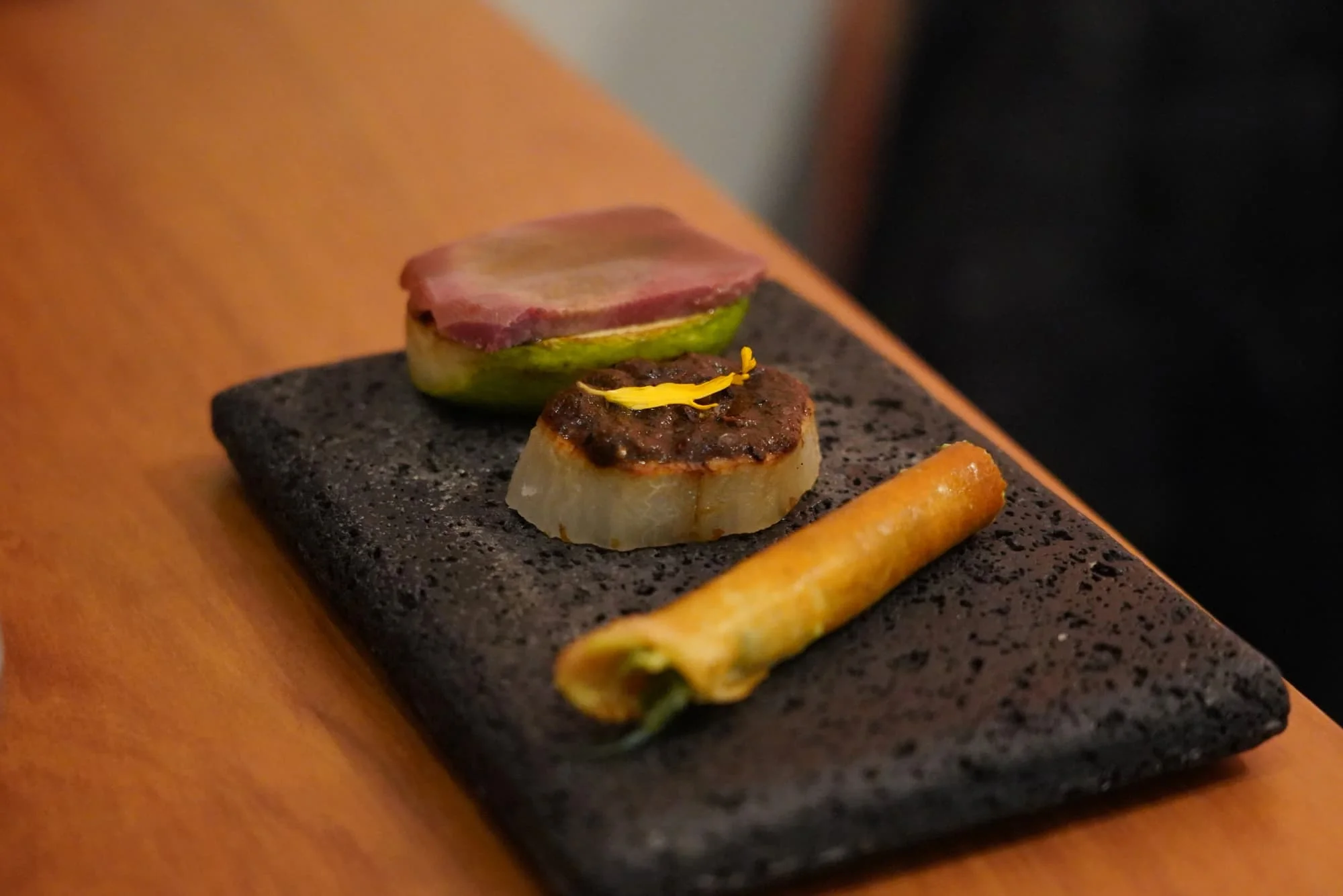 From front to back: A kind of dosa-like roll with cheese, herbs and sprouts; chinchayote, salsa and corn; and chilacayota with pickled beef on top.