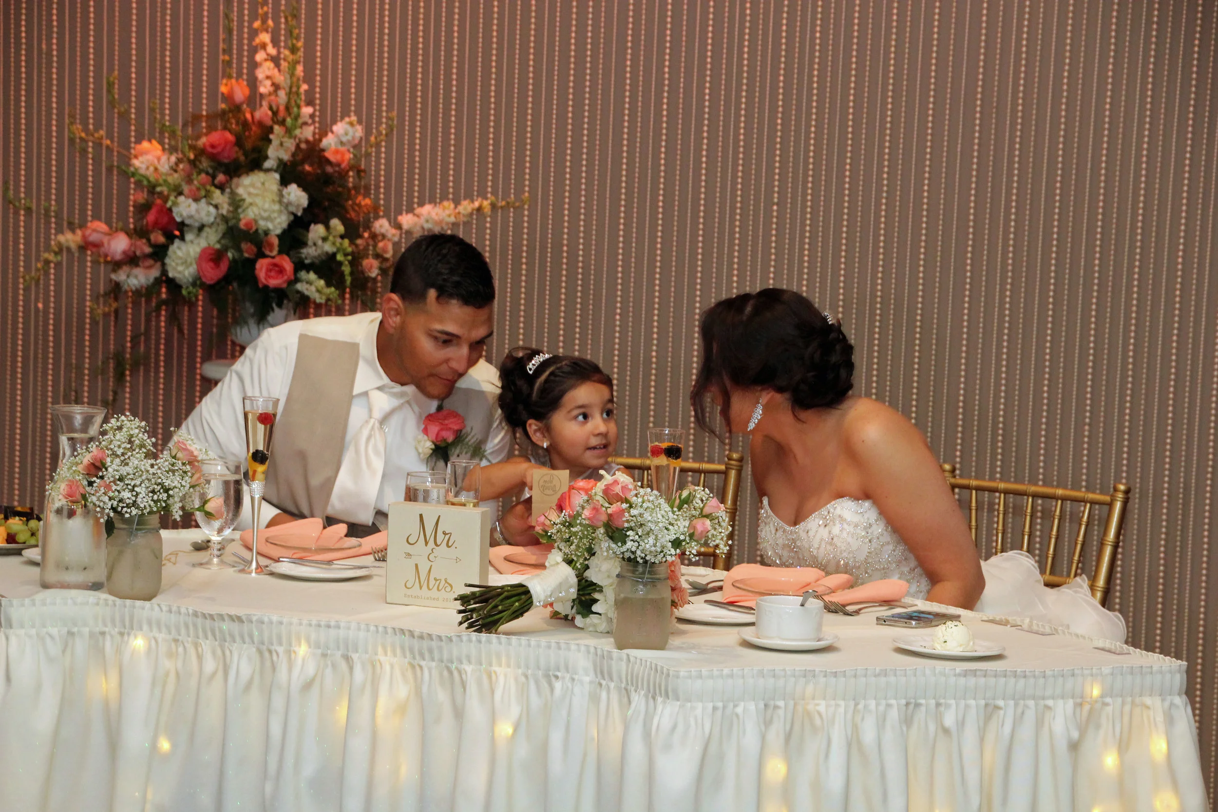 Crystal curtains behind a sweetheart table with floral arrangements (and fruit in every guests champagne glass!)