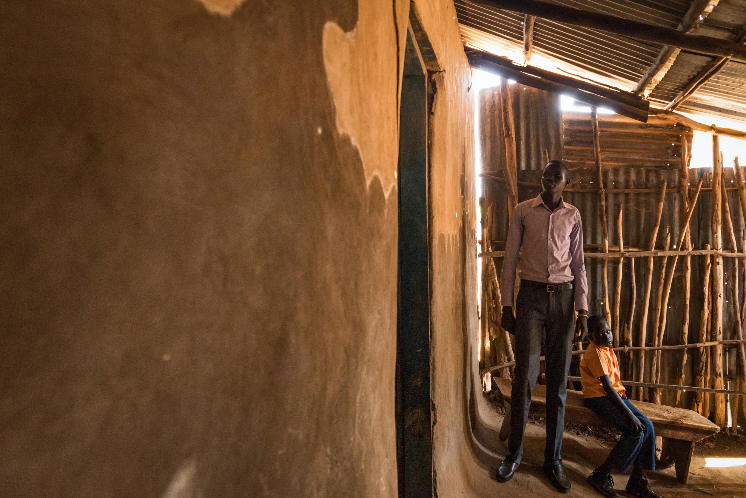 Dinka men wait outside the church in Arua, Uganda. Several avoided being photographed for fear they could be targeted for violence by soldiers loyal to Vice President Riek Machar, an ethnic Nuer.