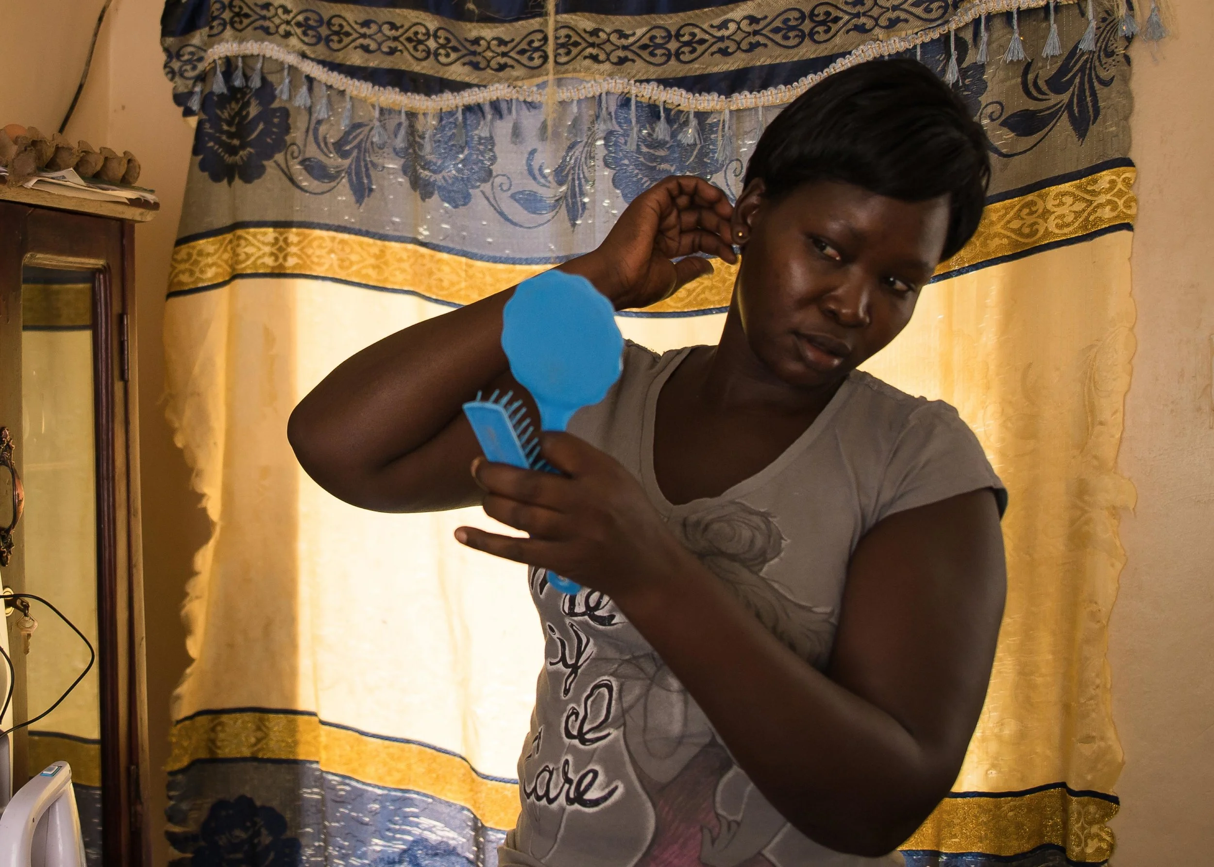 Alice prepares for the day inside her home in Arua, Uganda.