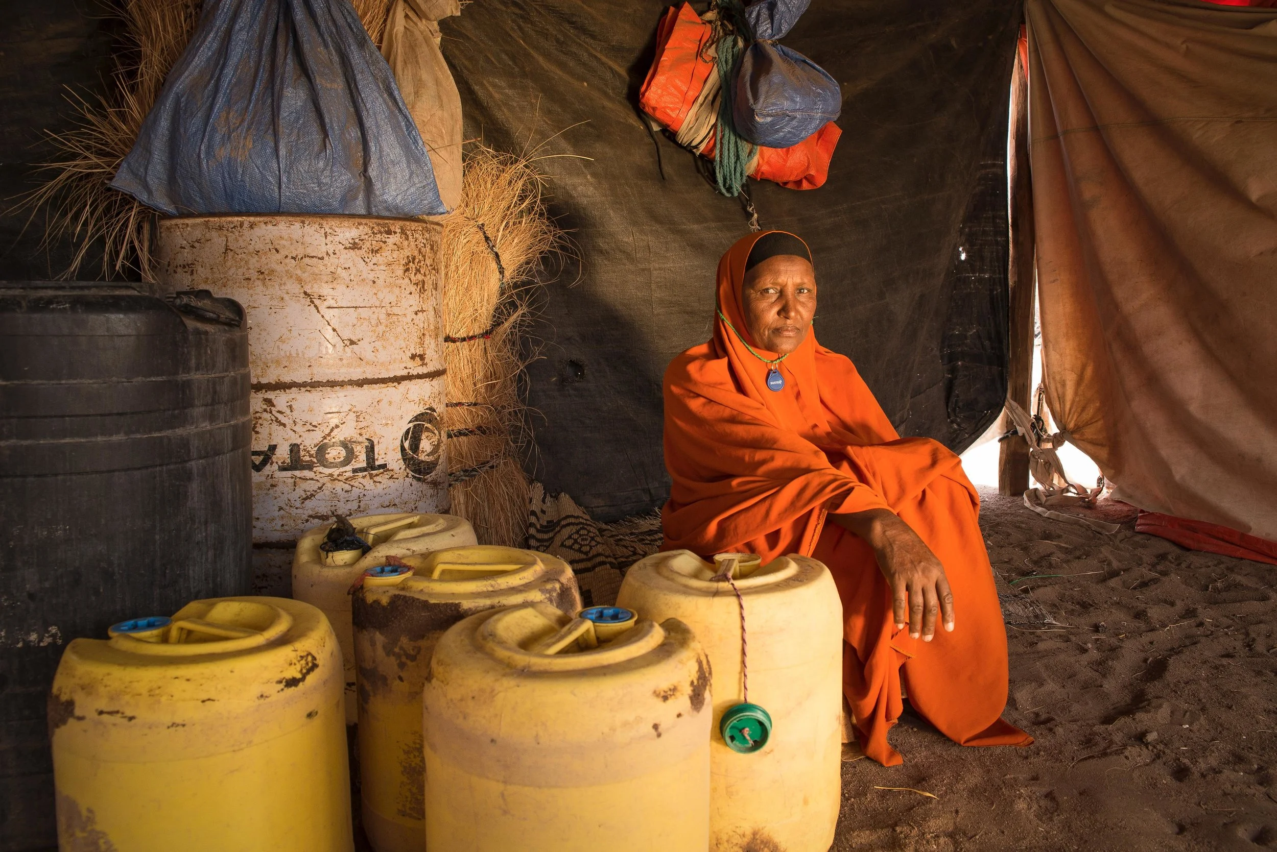 Bishara Abdi Iladir, 53, sits next to the Jerry Cans she uses to transport water from a pump to her home four times a day. The ongoing drought in the Horn of Africa forced Iladir’s husband to take their livestock to lusher land in the east, leaving her 30 children and grandchildren without fresh milk, meat or a means to survive. It has been four months since her husband left; she hasn’t heard from him since.