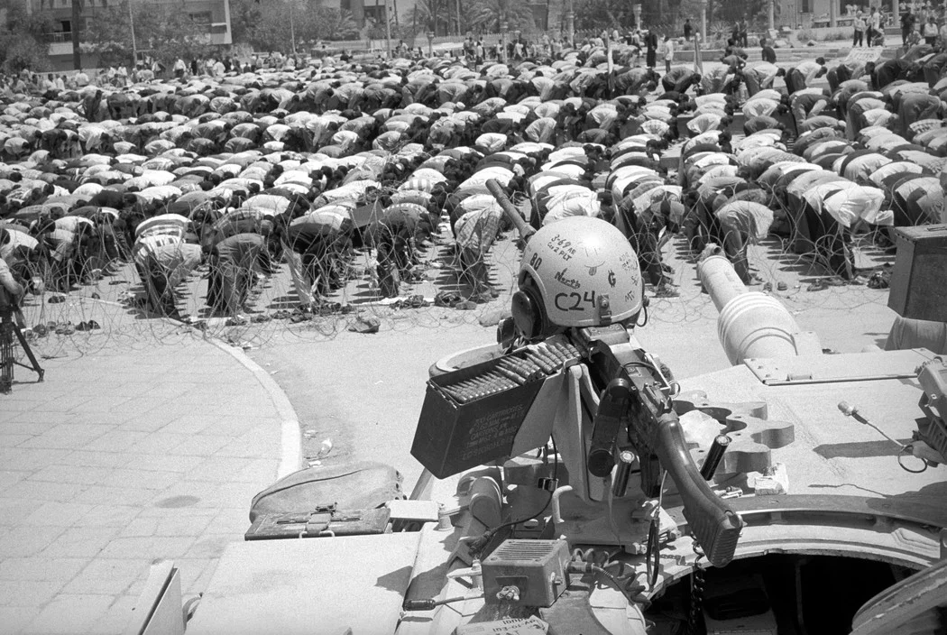 © A. Abbas/Magnum Photos: IRAQ. Baghdad. After a rally against the American presence in their country, Shias perform their midday prayer under the canon and the machine gun of an Abrams US tank.
