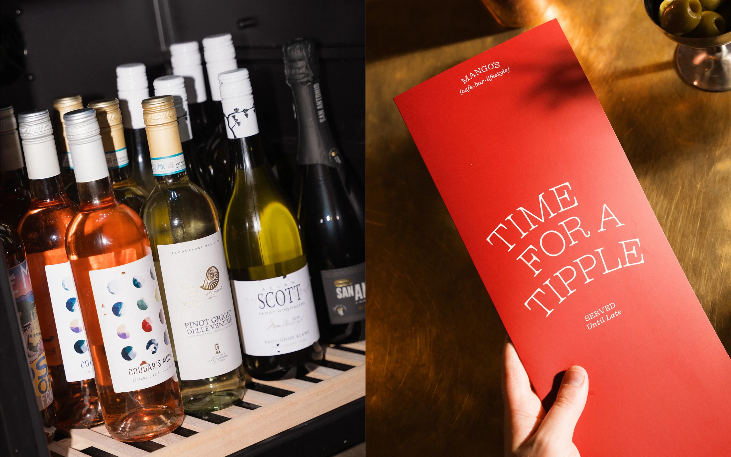 Wine bottles beside a red Mango’s cafe bar menu on a wooden table with olives