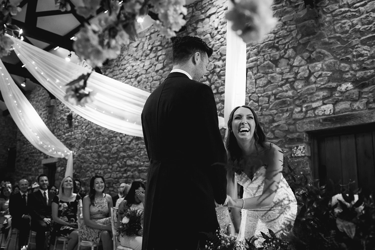  black and white photo of bride laughing during ceremony 