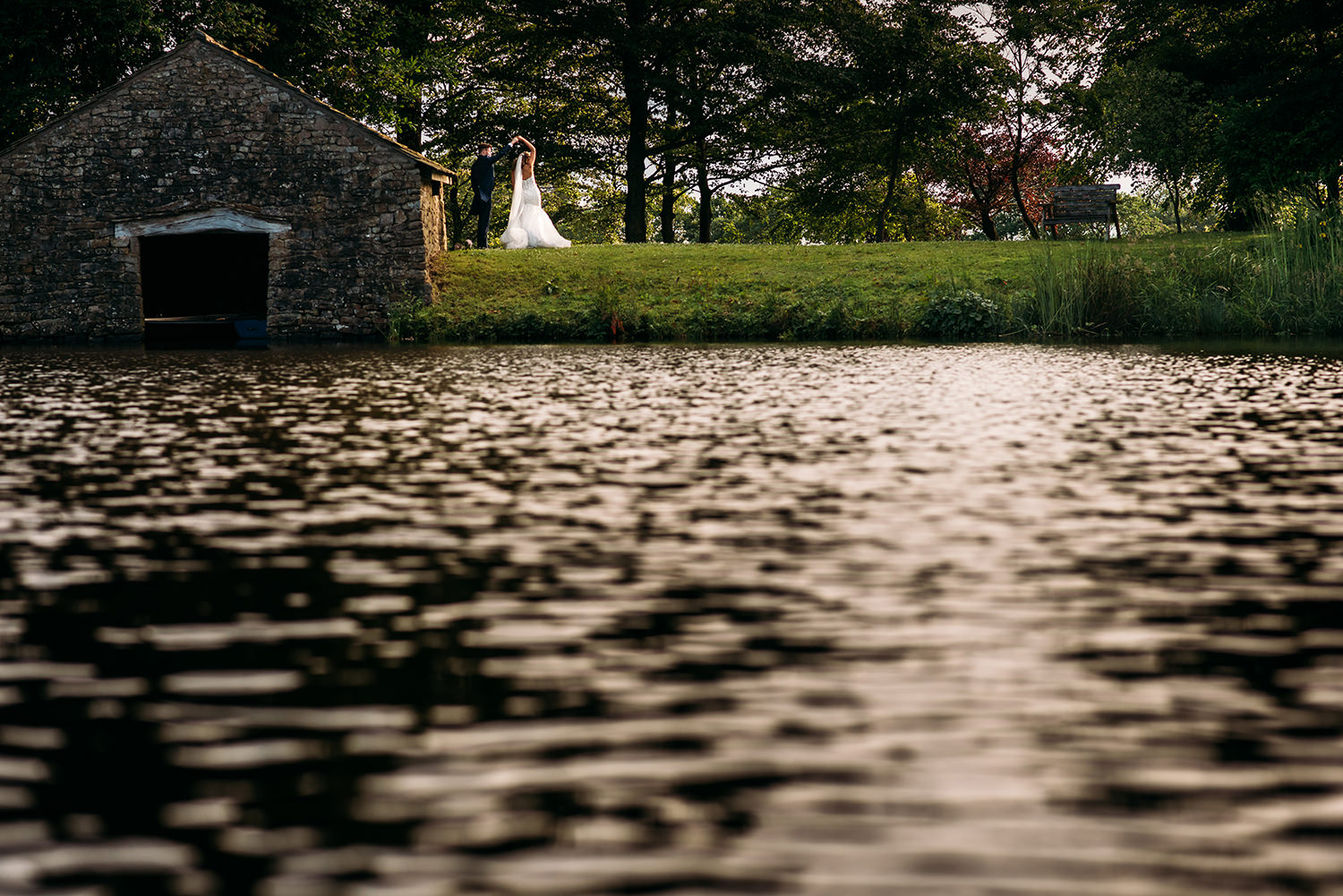 colour photo of bride and groom dancing by the lake