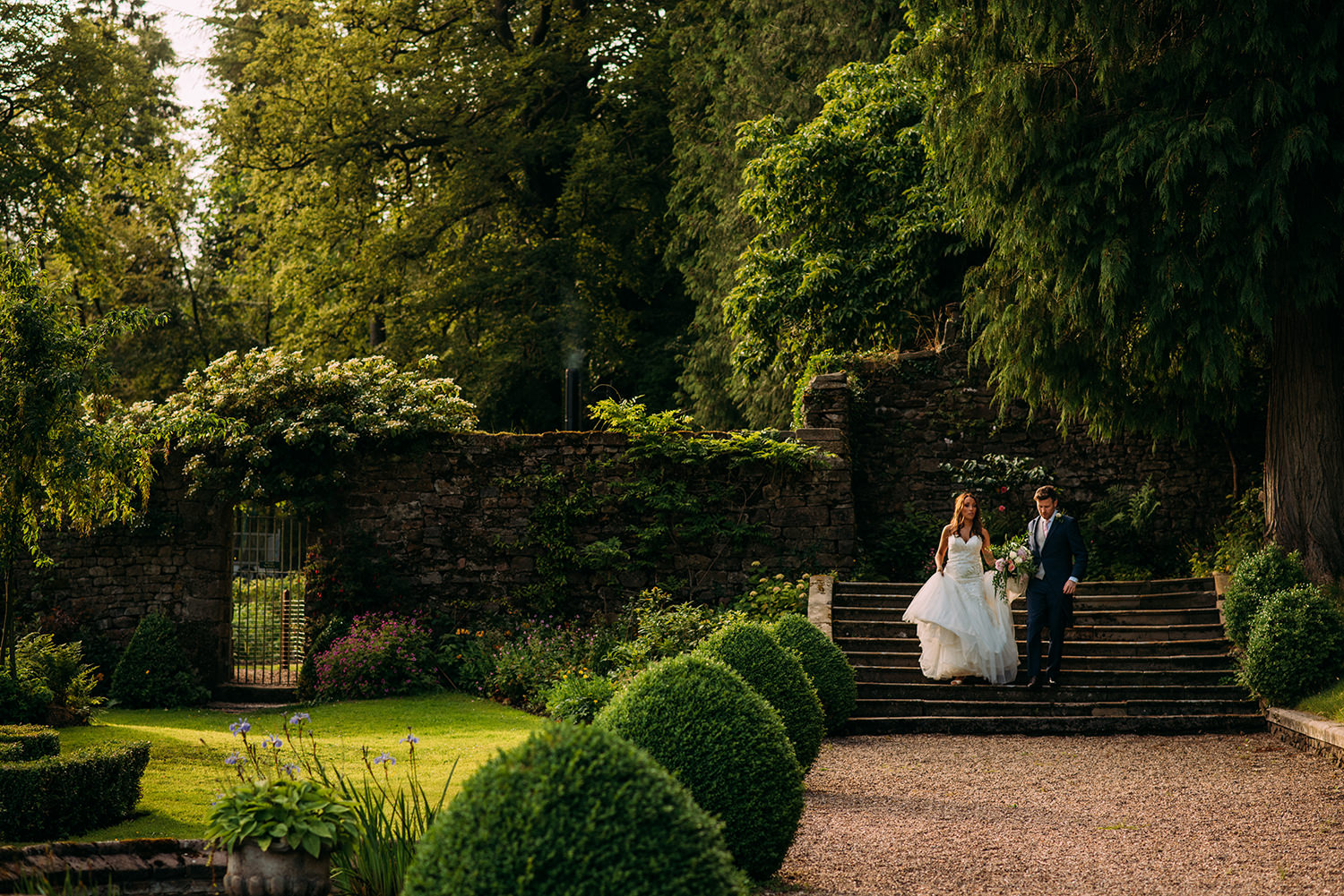  colour photo of bride and groom walking through the grounds 