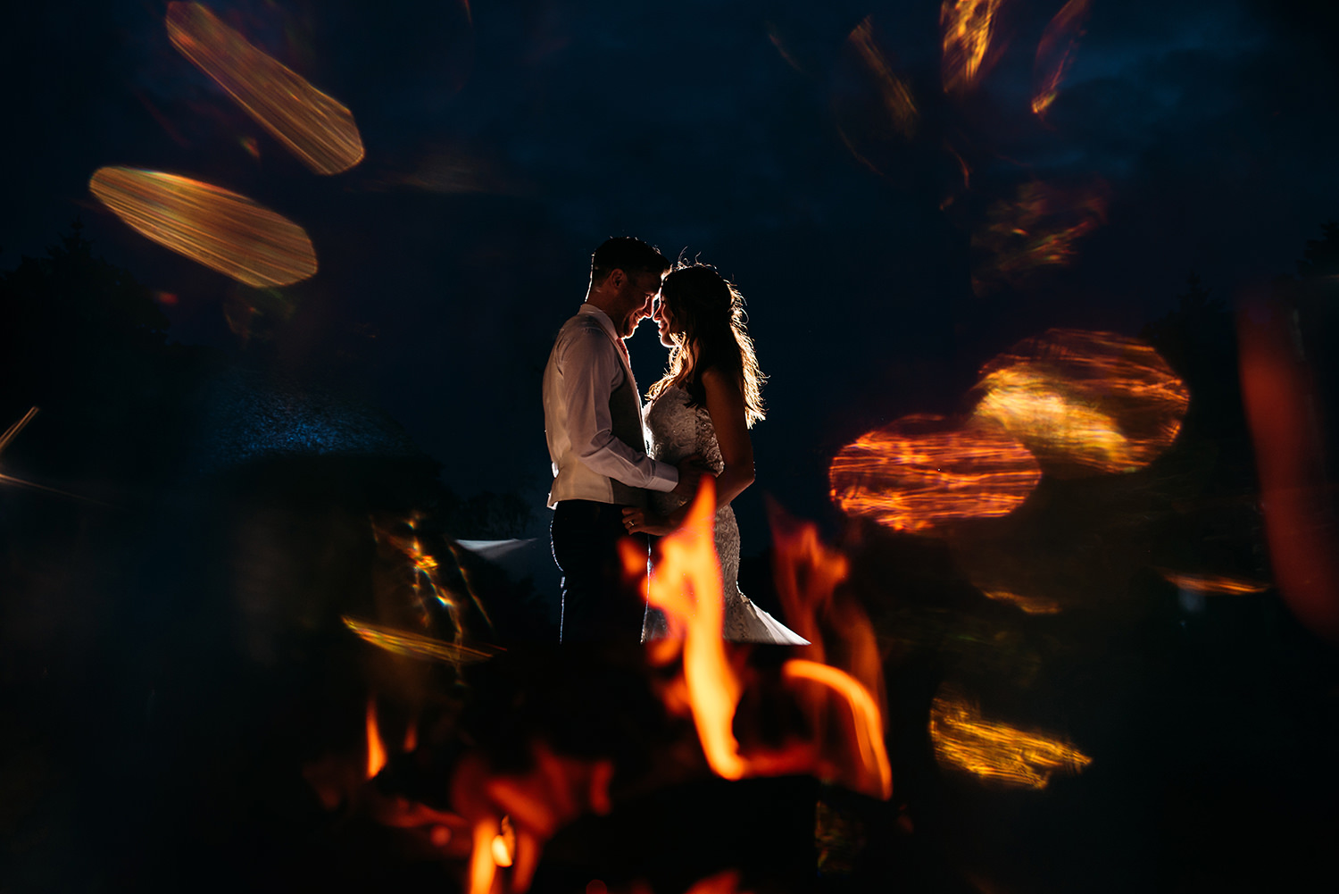  colour photo of bride and groom by a fire pit 