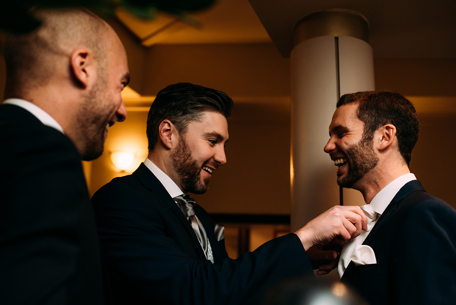  groomsmen adjusting grooms tie 