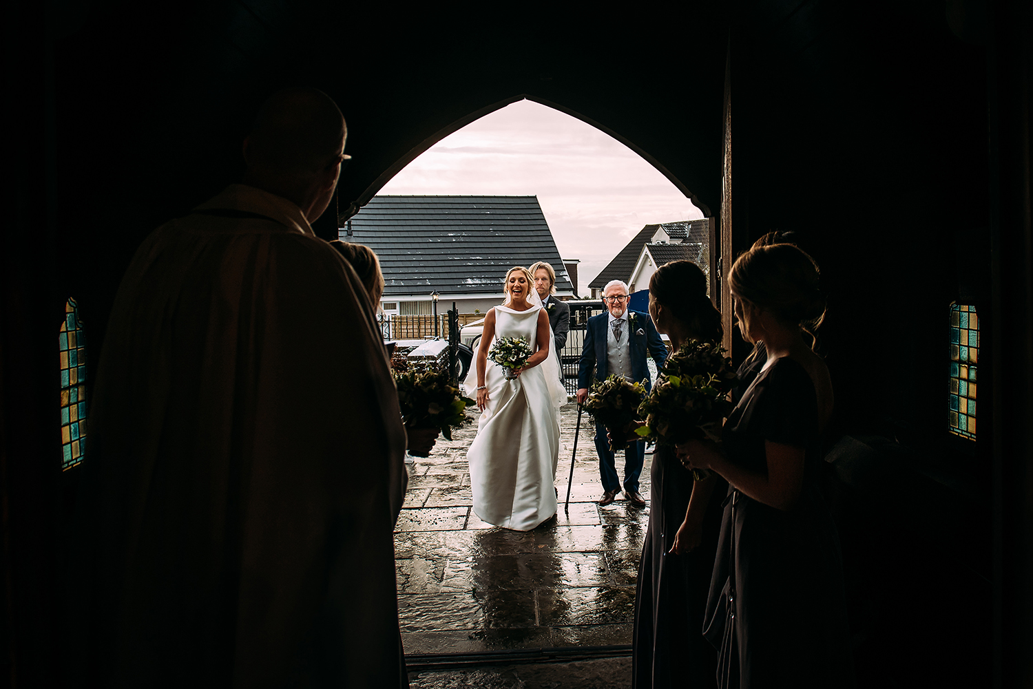  bride and father walking up church path, shot through the church door 