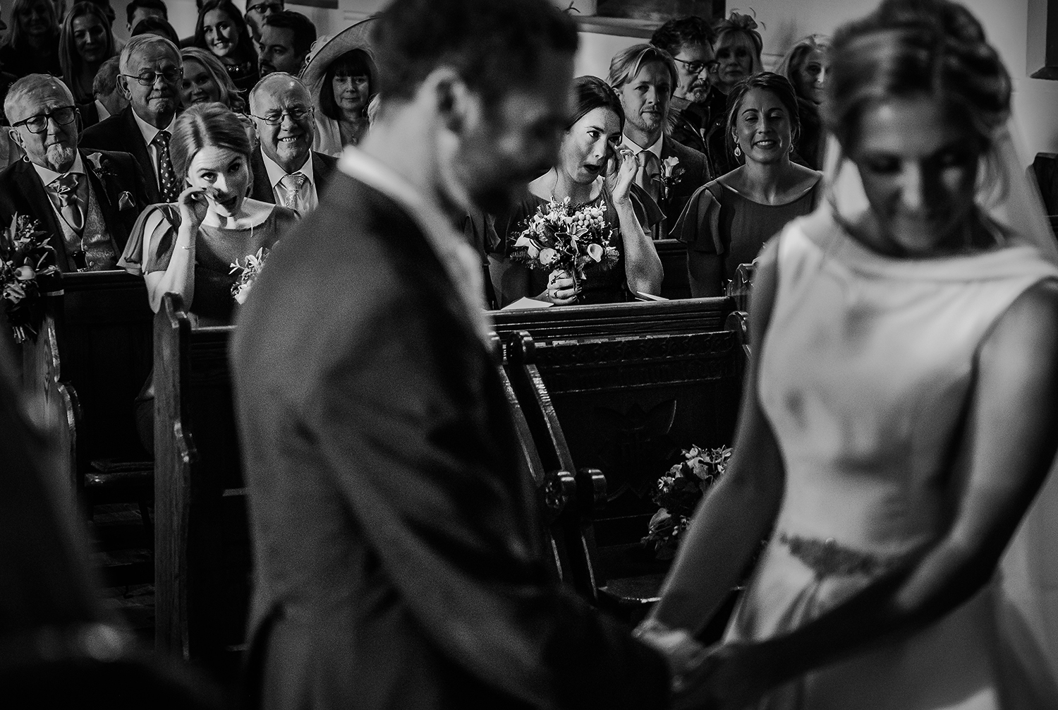  Black and white photo. Two bridesmaids wiping tears from their eyes at the same time 