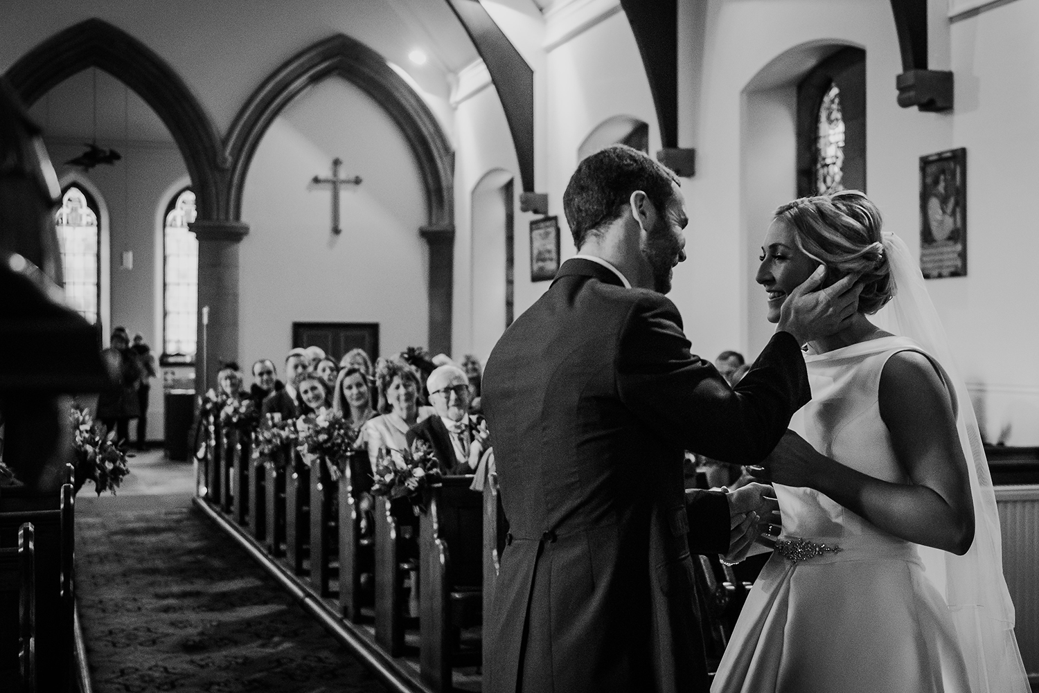  Black and white photo of the grooms hand on the brides face about to kiss 