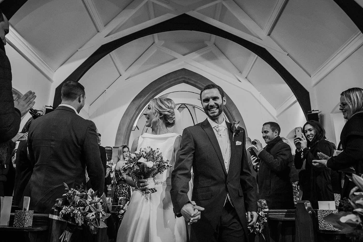  black and white photo of the the bride and groom leaving church 