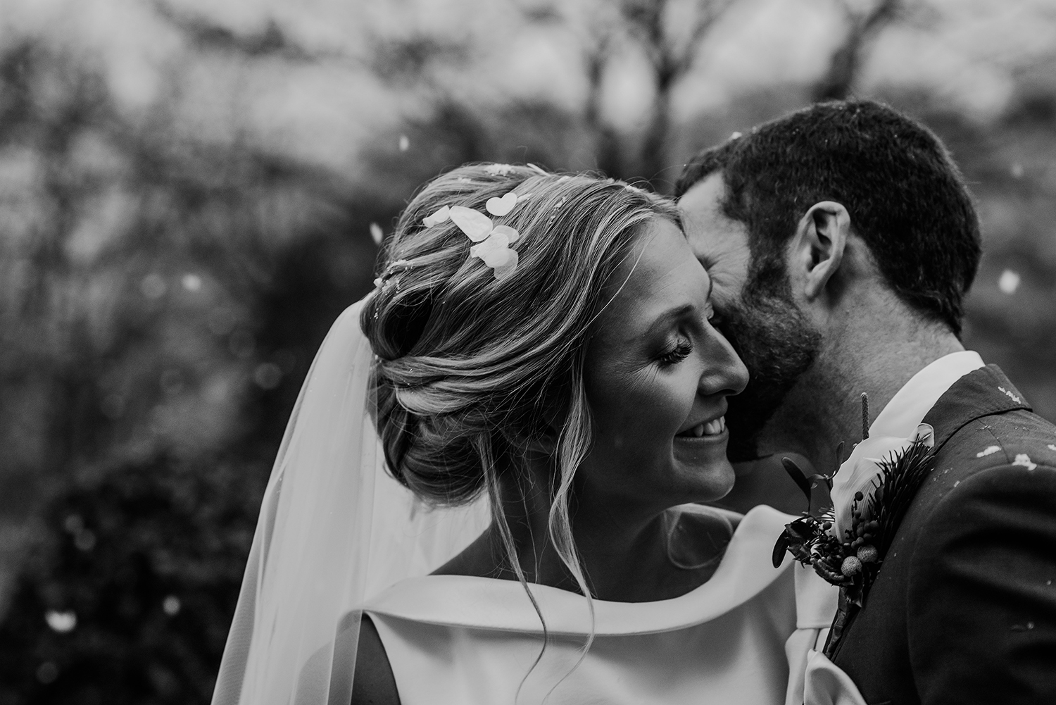  Black and white photo of the groom kissing the bride in the snow 