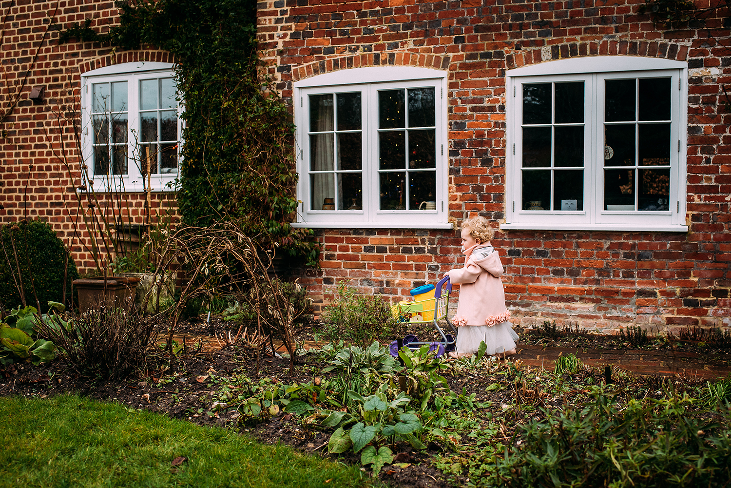 bride and grooms daughter pushing pram past family home to church
