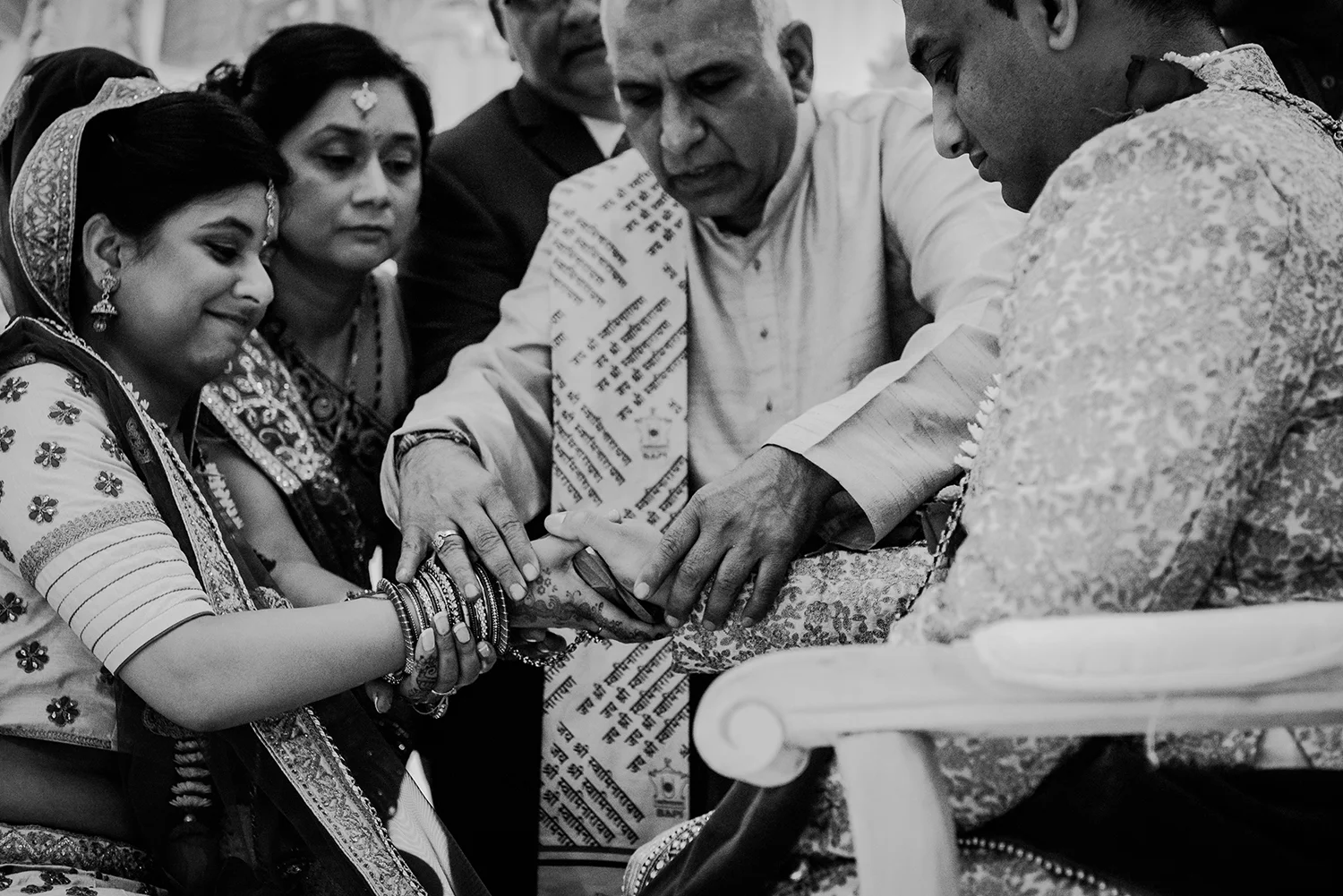 bw photo of the priest joining the bride and grooms hands