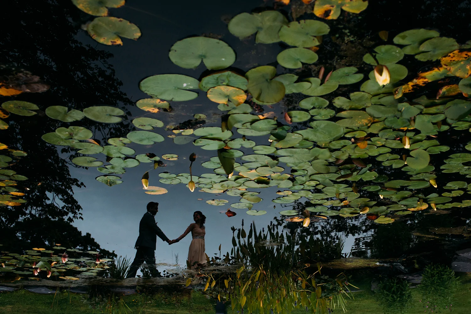 reflection of bride and groom in a pond