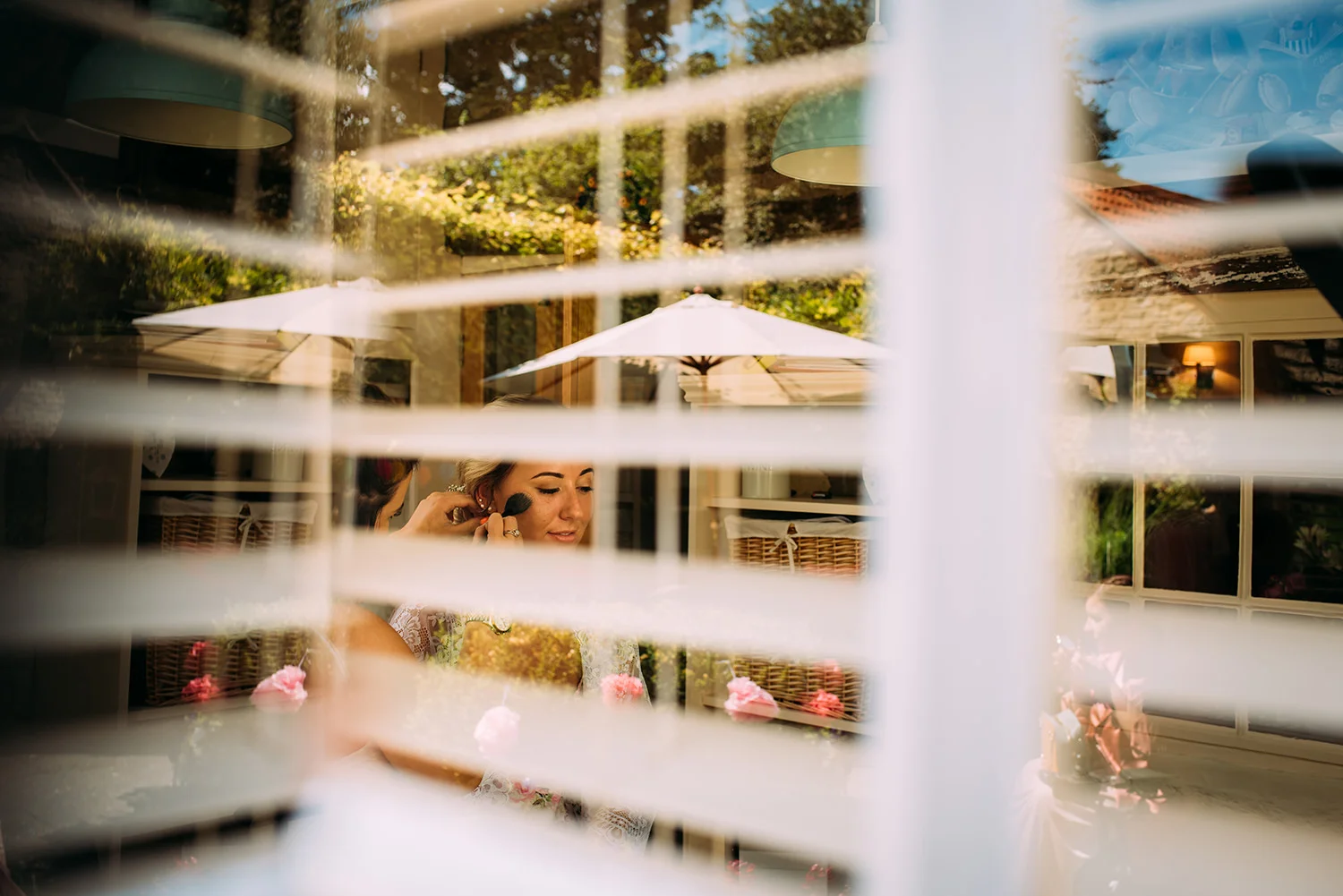 bride having make up done, shot through the window and blinds.