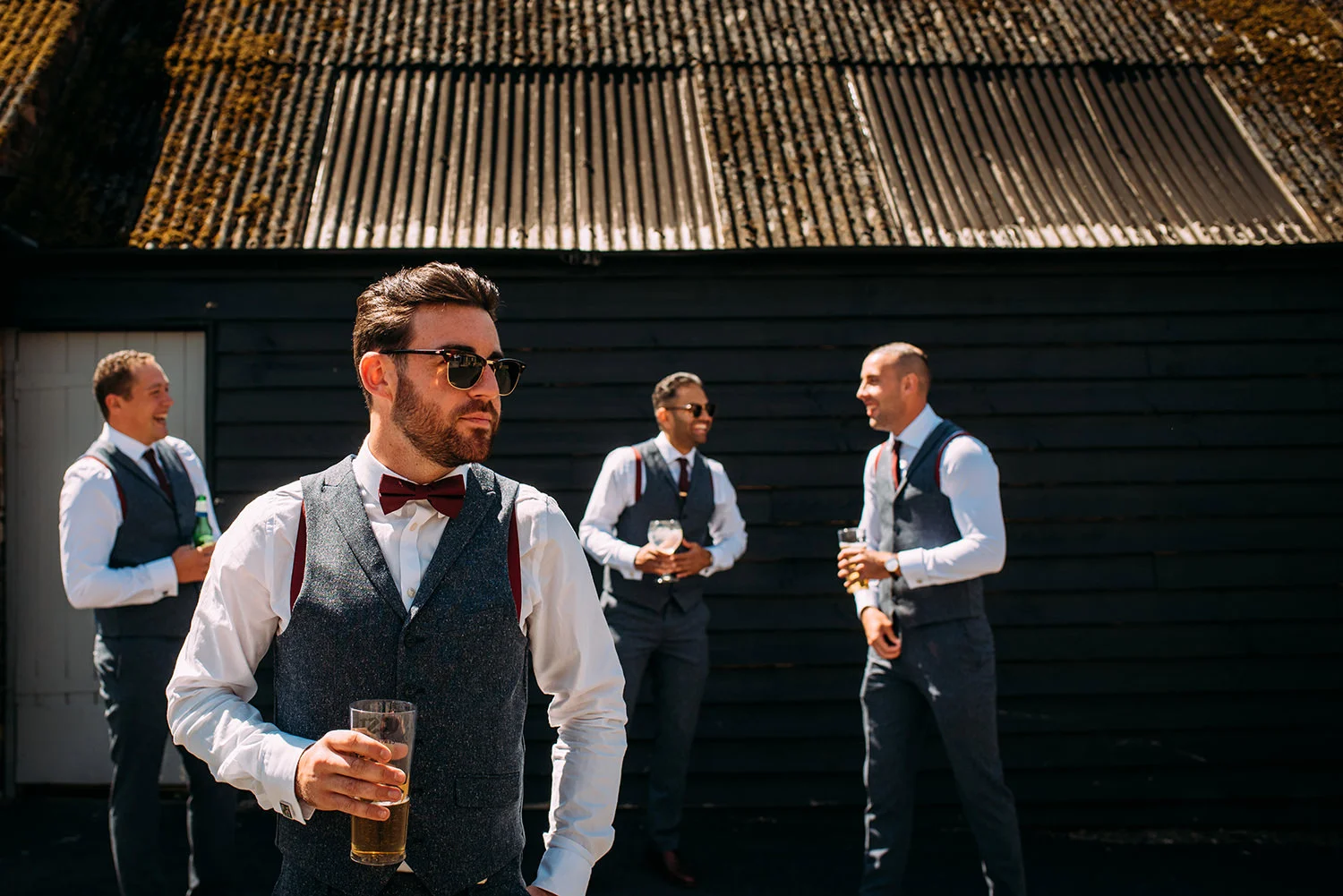 cool shot of the groom and his men by a shed in strong light