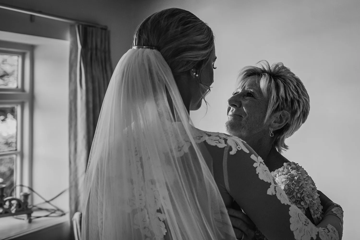 bw photo of bride’s mum hugging bride and looking proud