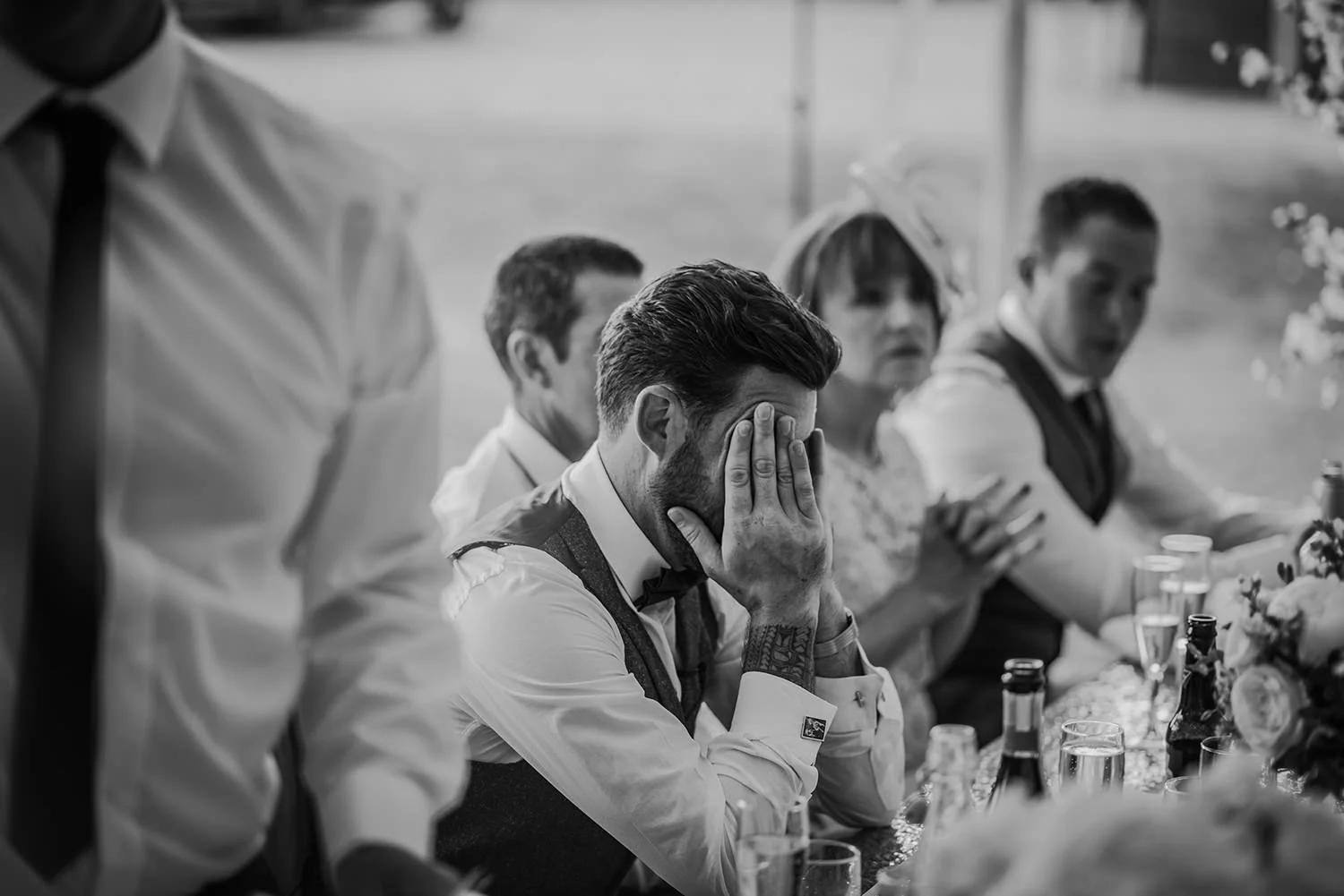 bw photo, groom head in hands during the speeches