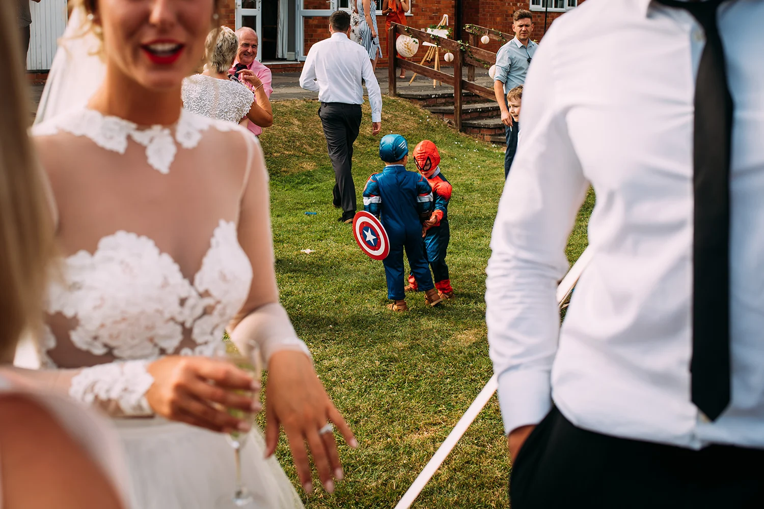 Spiderman and captain America scuffle in the backround of a normal guest mingling shot