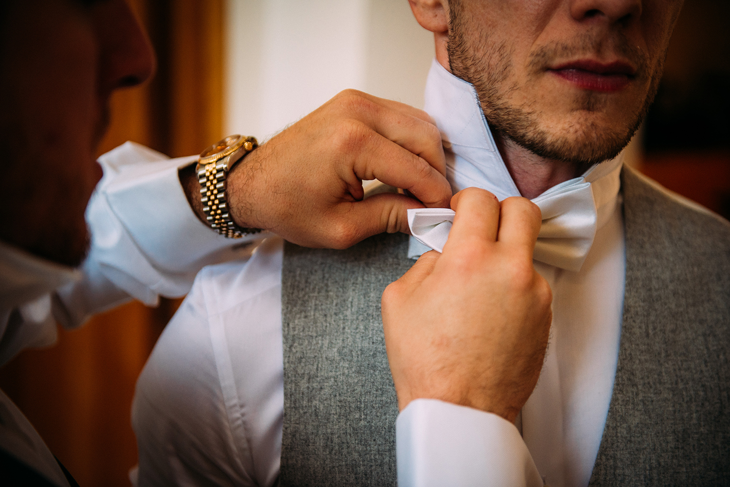 close up of groom’s bow tie being done