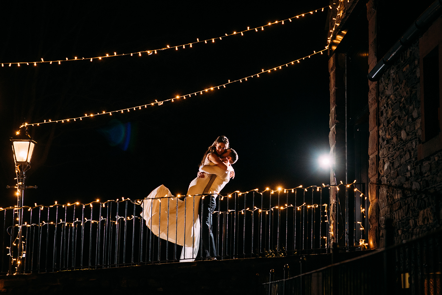 night time shot of the groom lifting the bride in the air