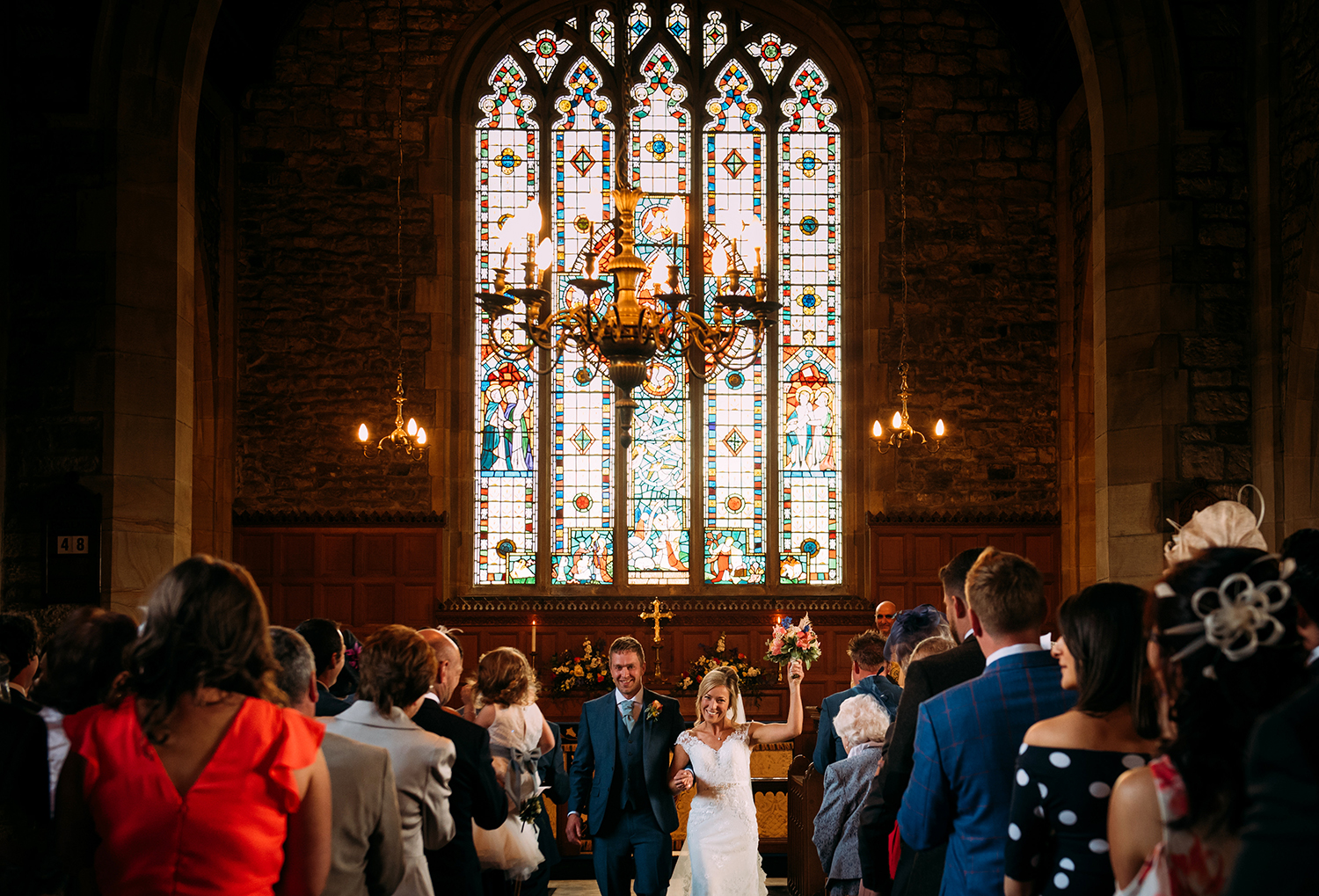 bride holds flowers up and they leave church together