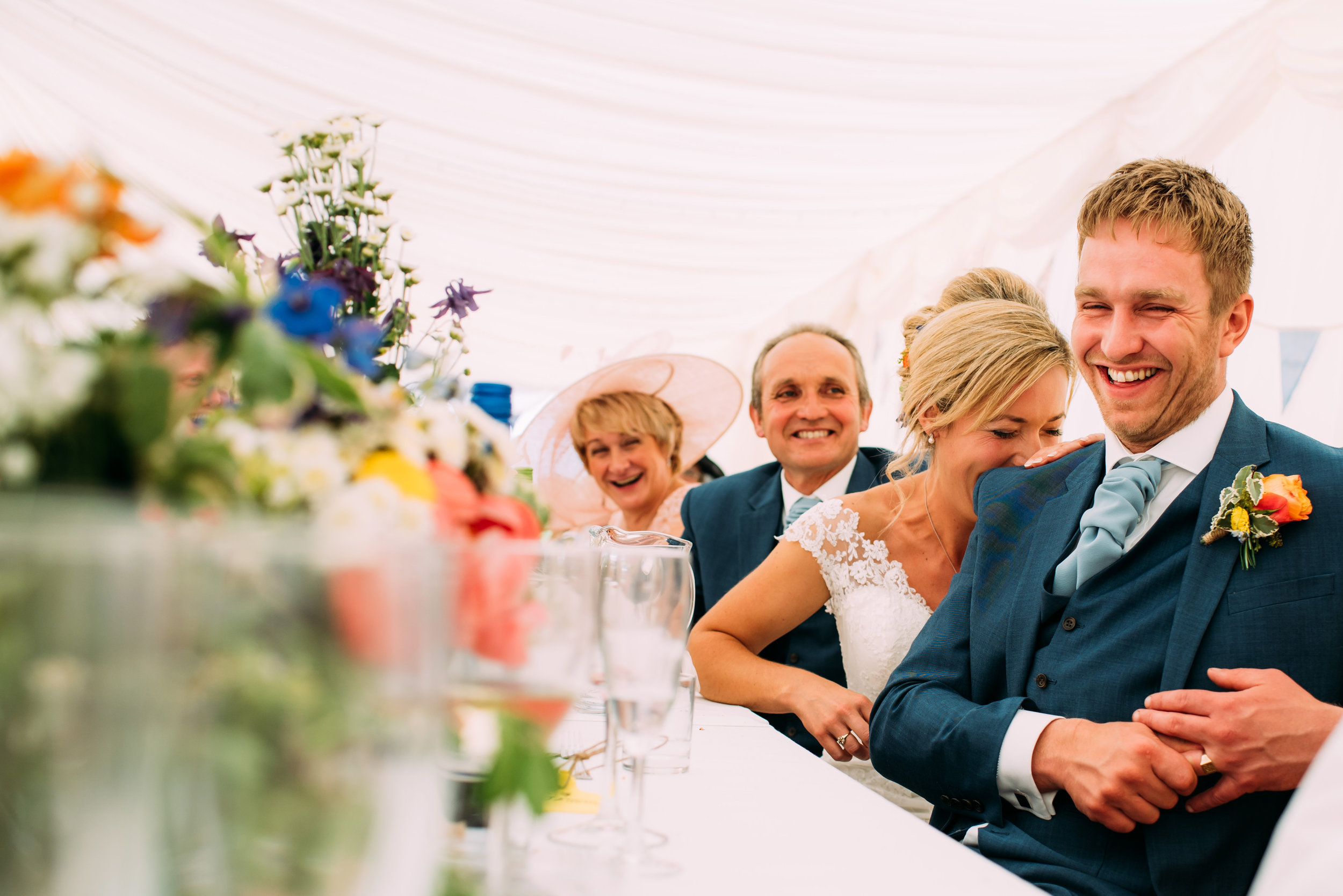 the bride laughs on the grooms shoulder during the speeches