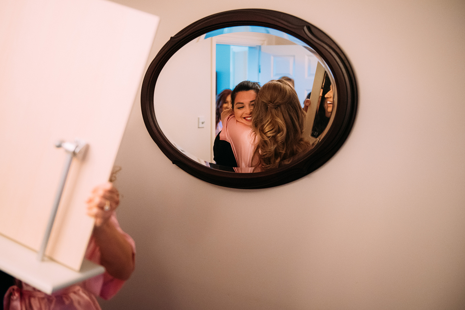 Mirror reflection of the bride hugging her friend
