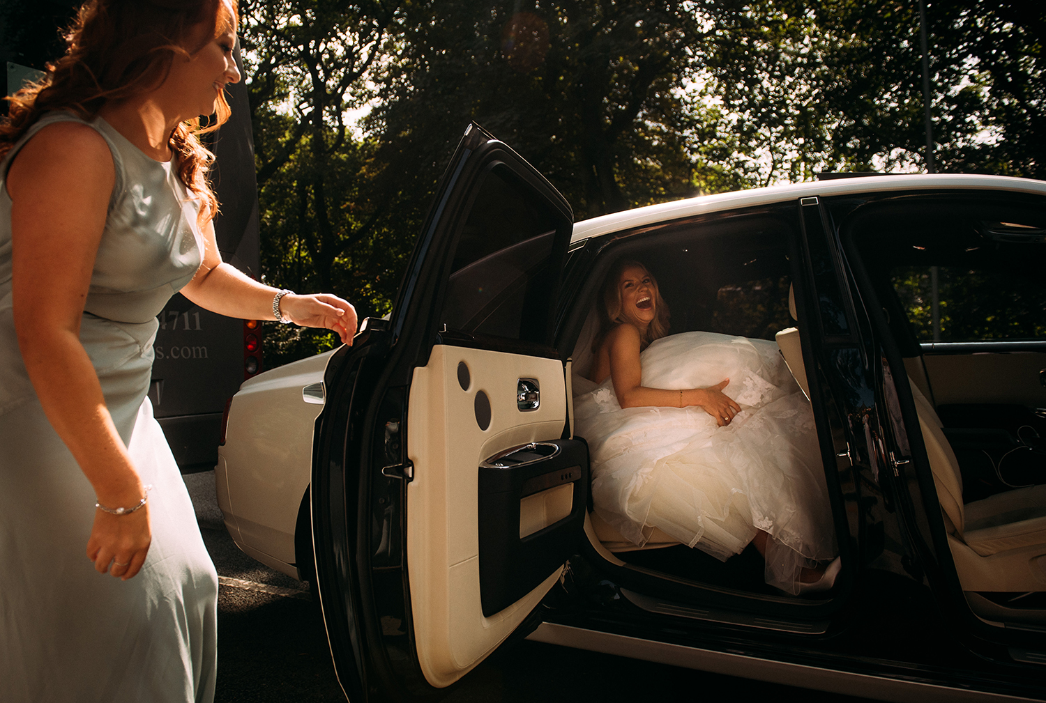  brides sister helping her out of the wedding car 