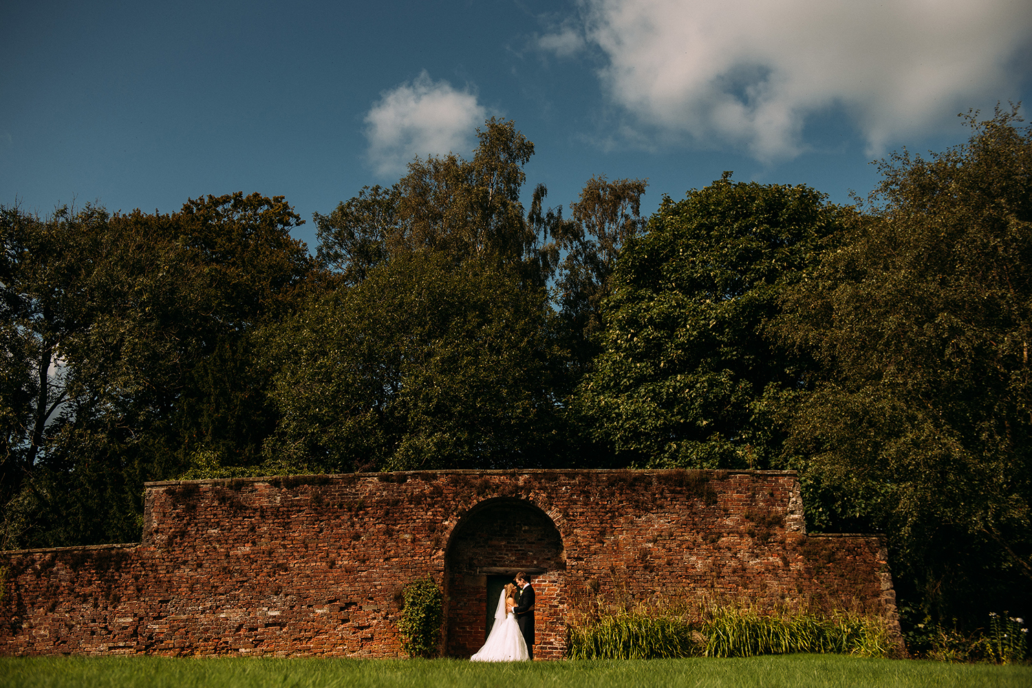  bride and groom kissing in front of a huge wall 