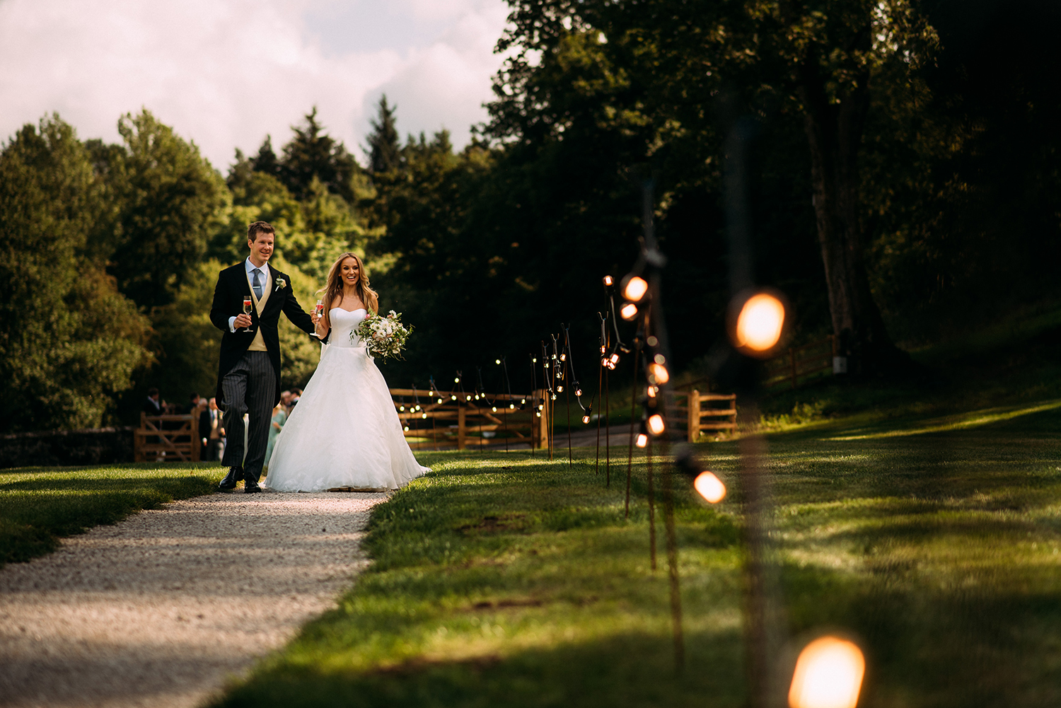  bride and groom walking along a fairy lit path to the marquee 